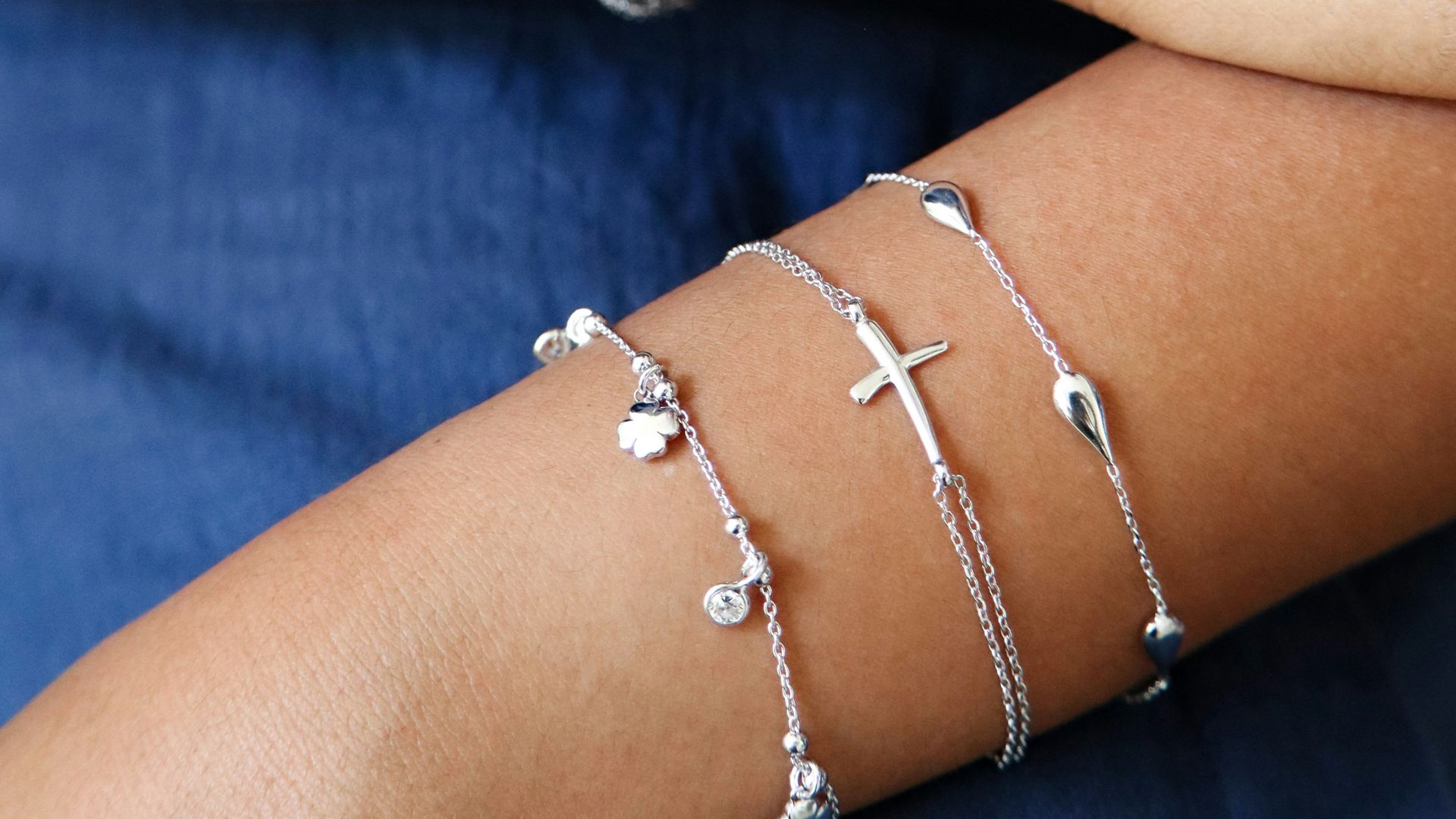 Two arms adorned with delicate silver bracelets.