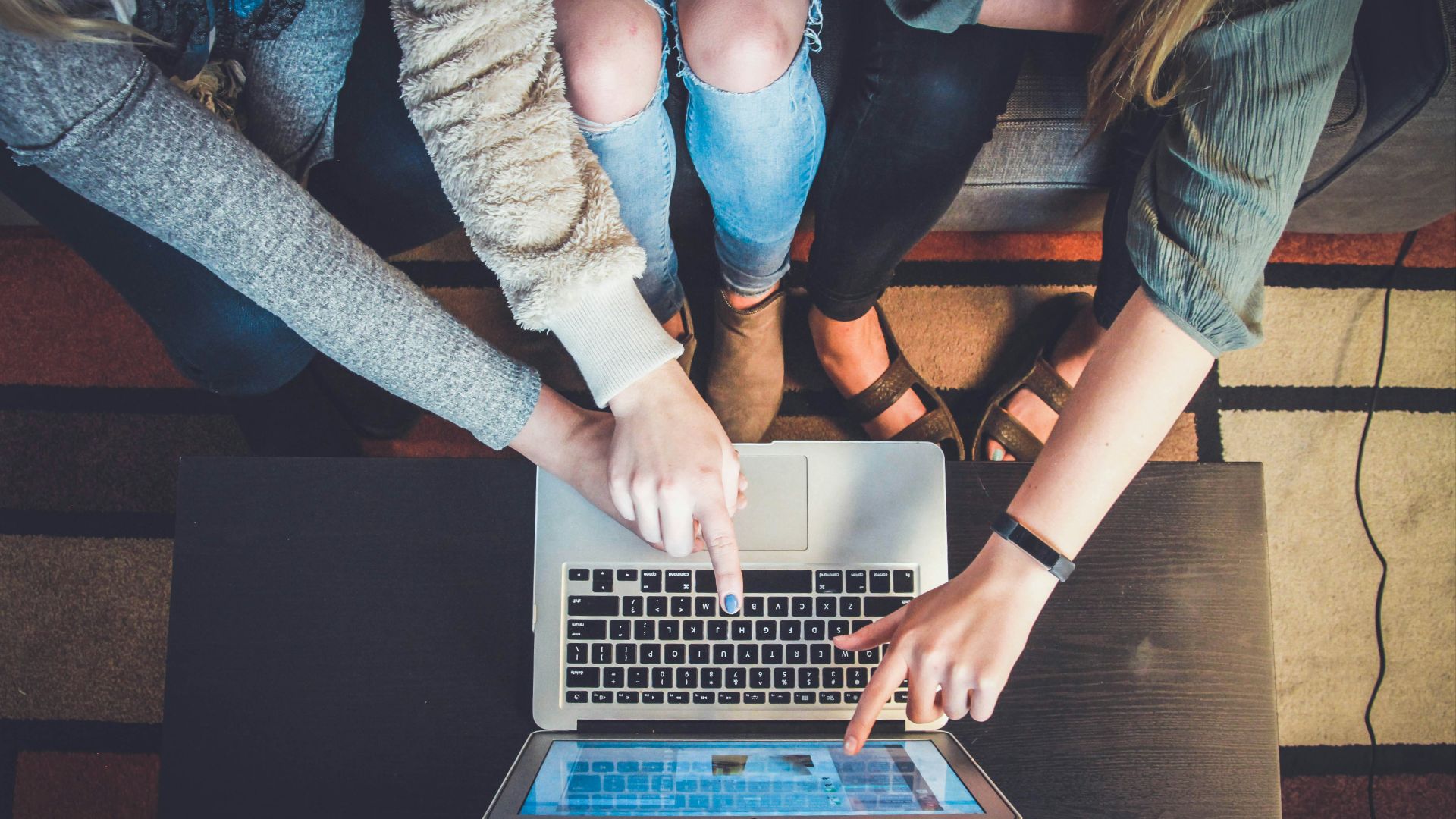 three person pointing the silver laptop computer