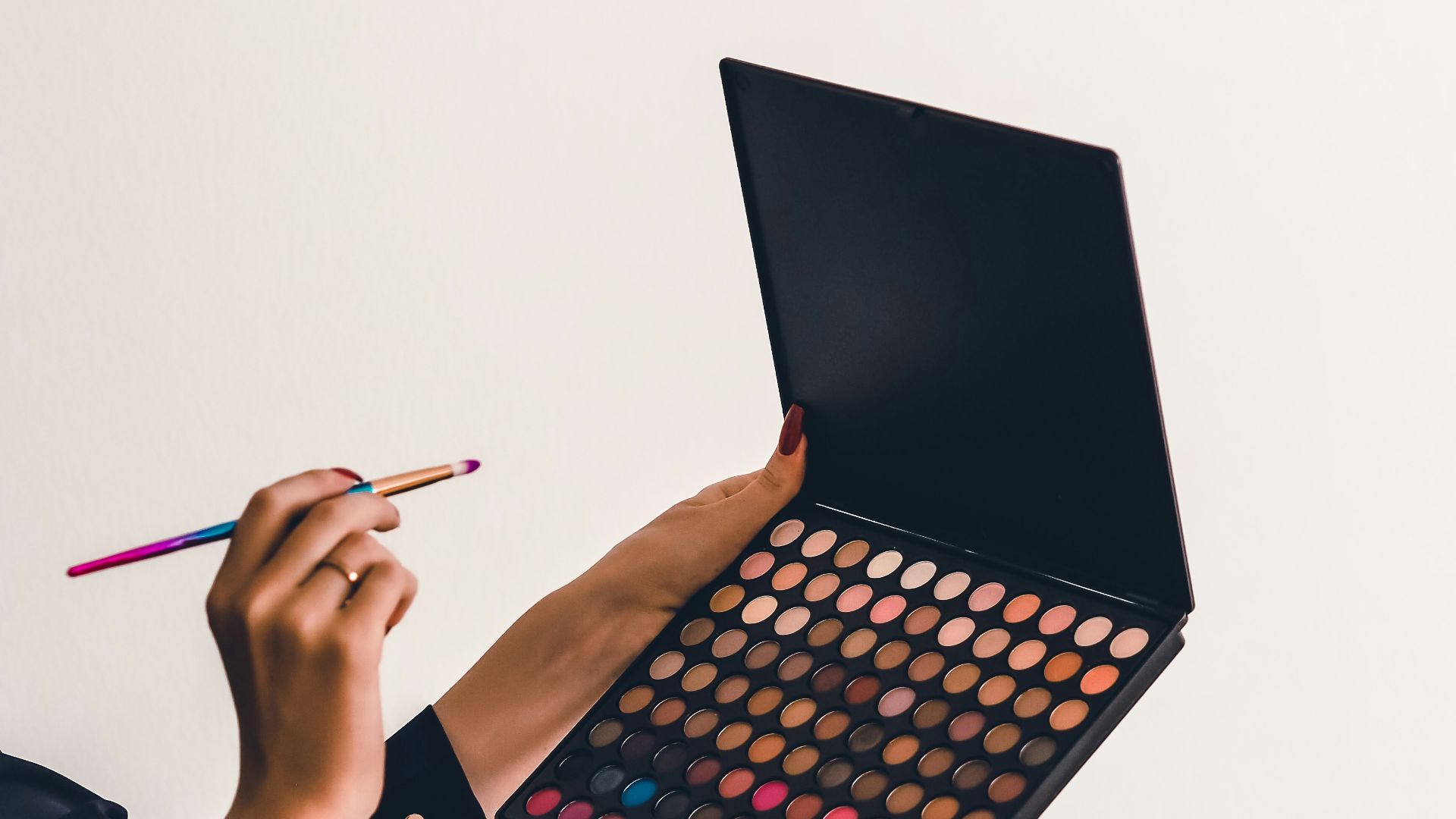 a person holding a makeup palette and a pencil