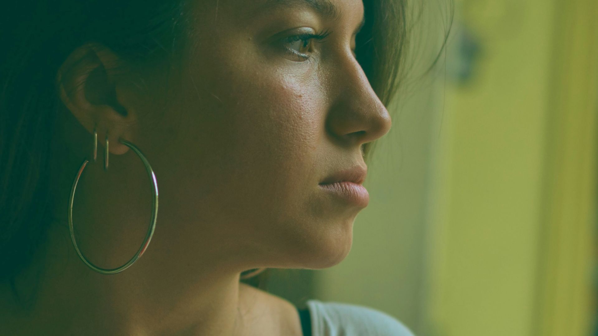 Young woman with hoop earring looking out window