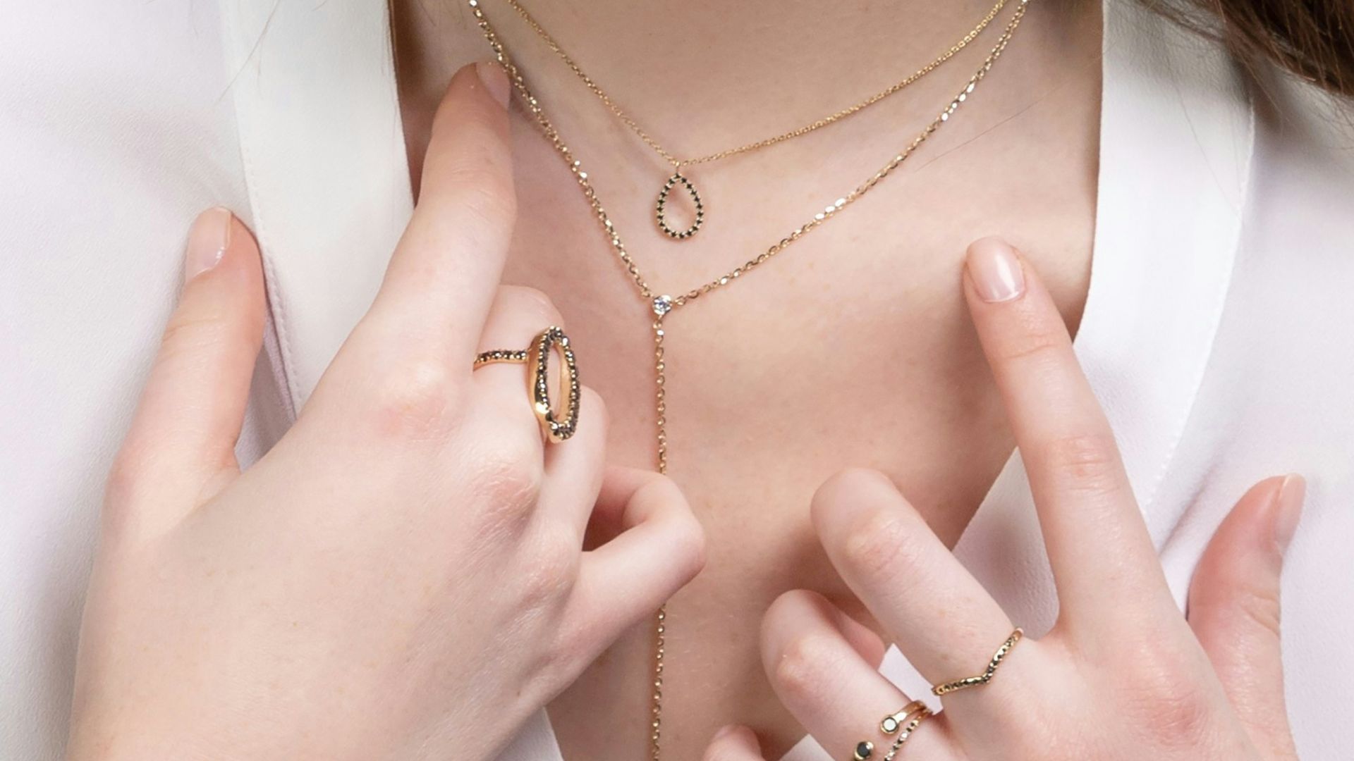 a close up of a person wearing rings and a necklace