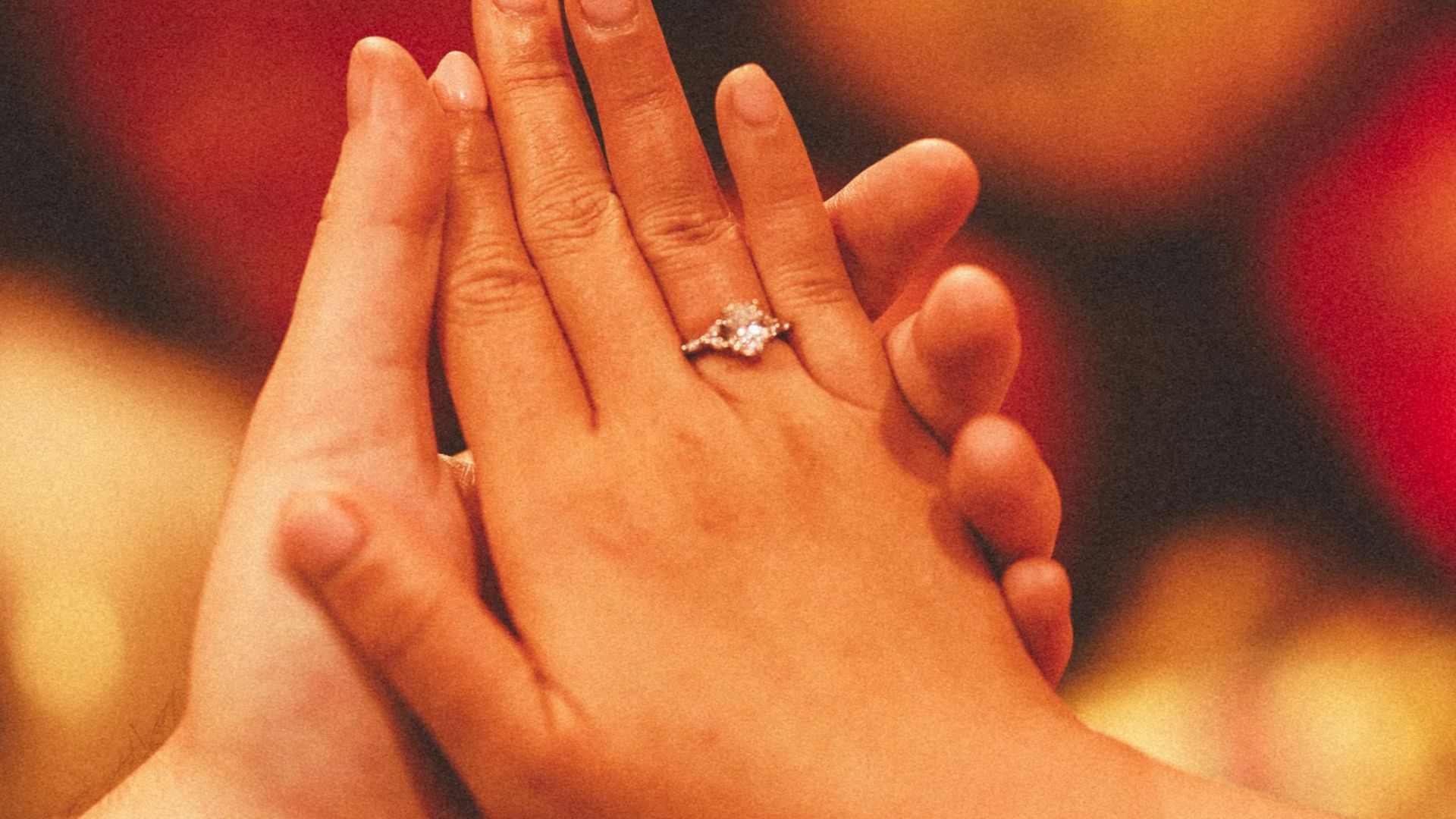 Couple holding hands with engagement ring.