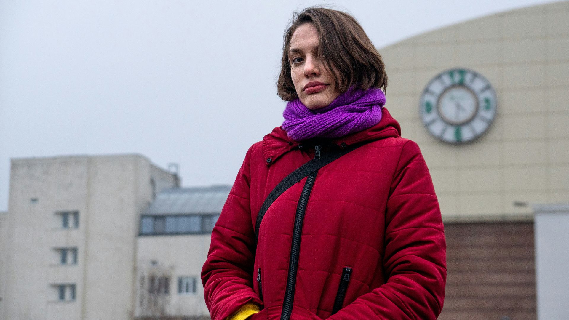 A woman standing in front of a building with a clock in the background