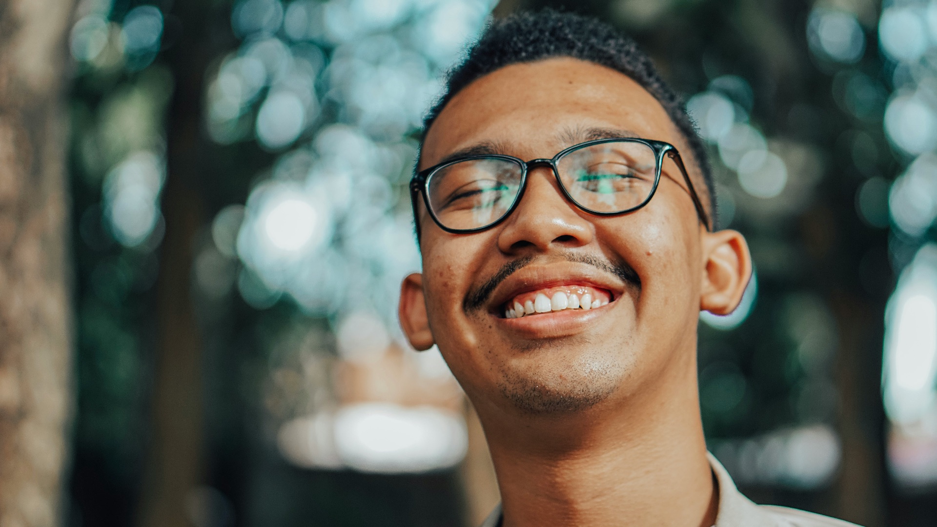 man in beige jacket smiling while wearing eyeglasses