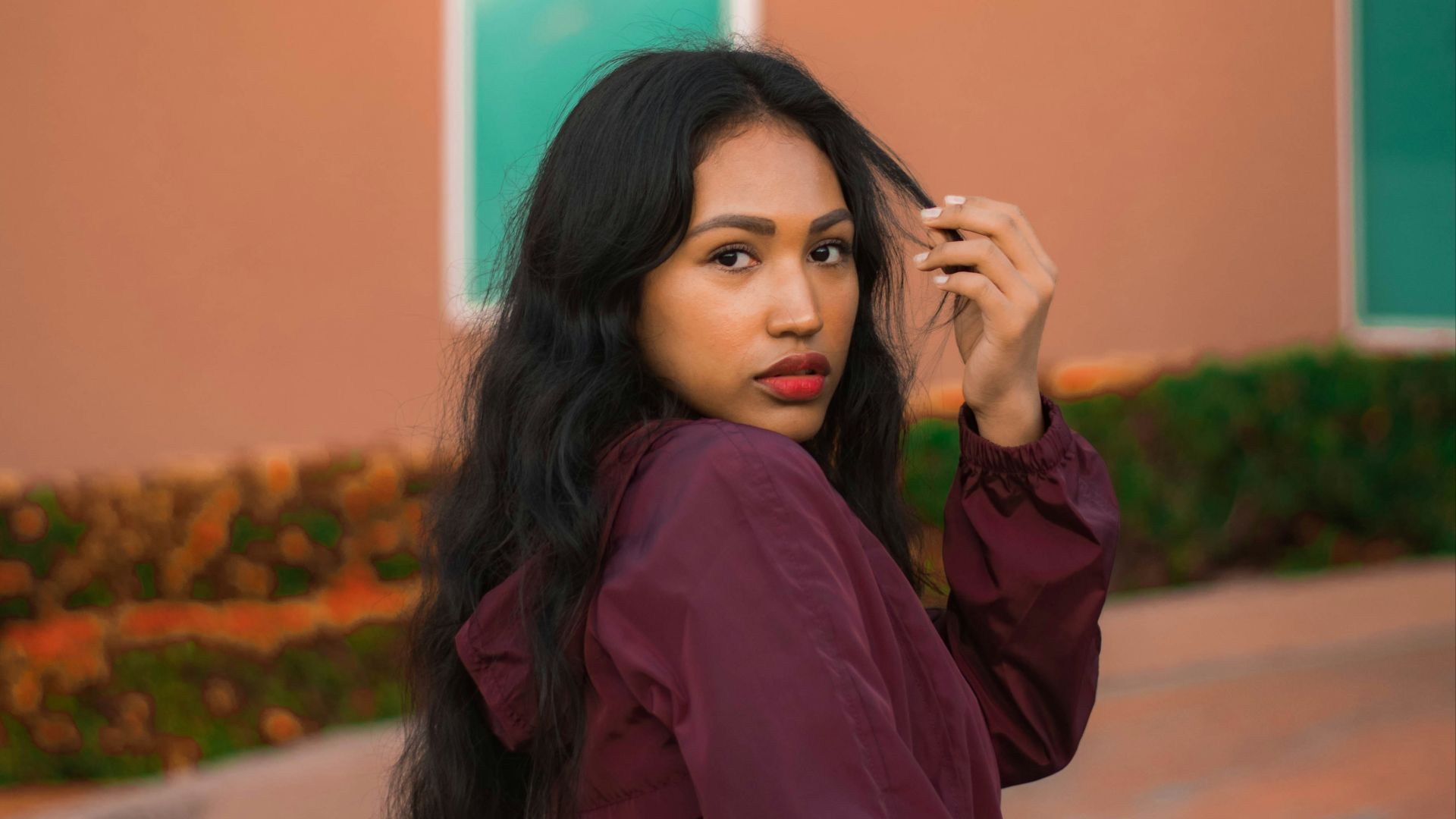 woman in purple long sleeve shirt standing near orange wall