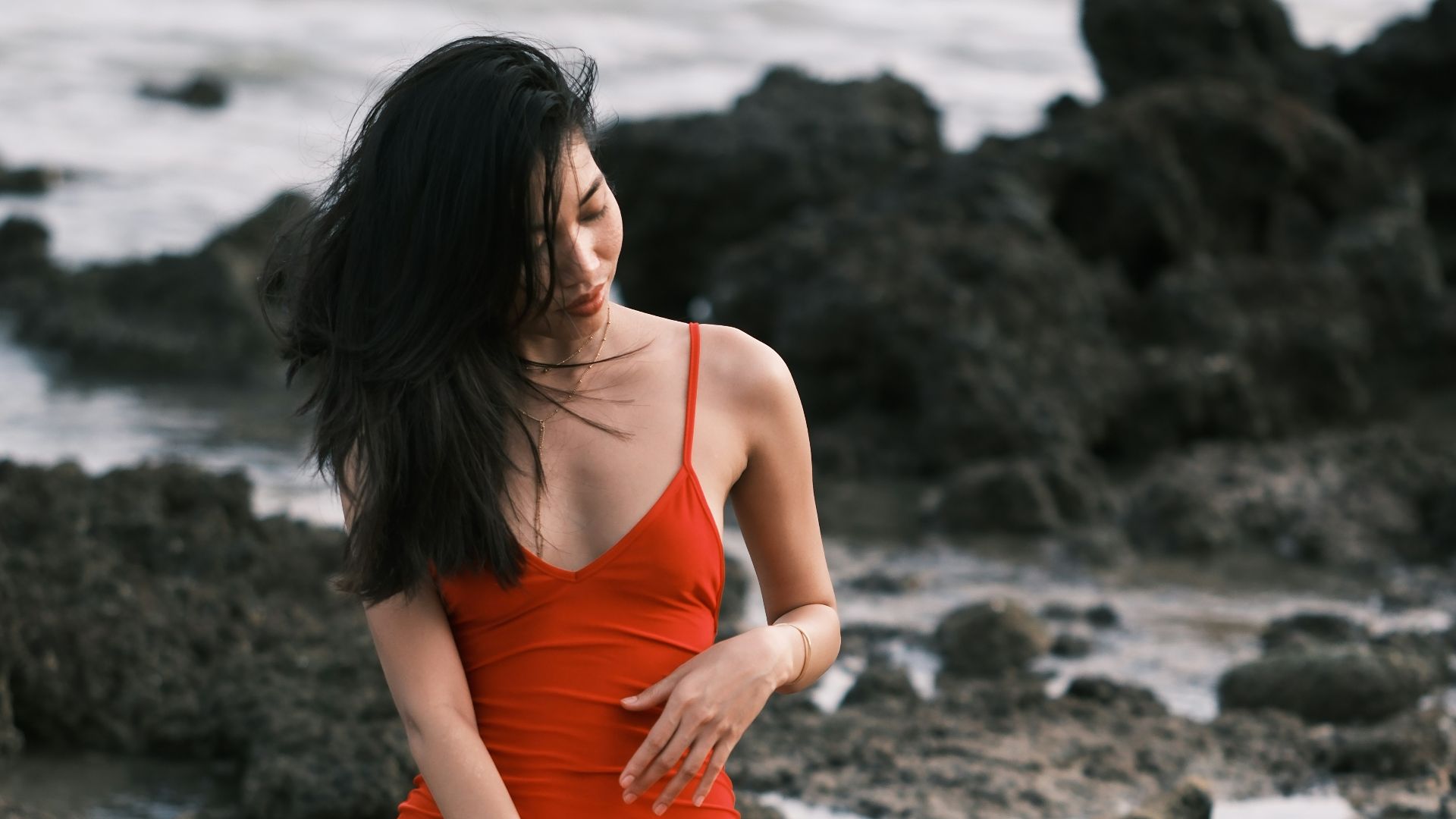 A woman in a red dress sitting on rocks