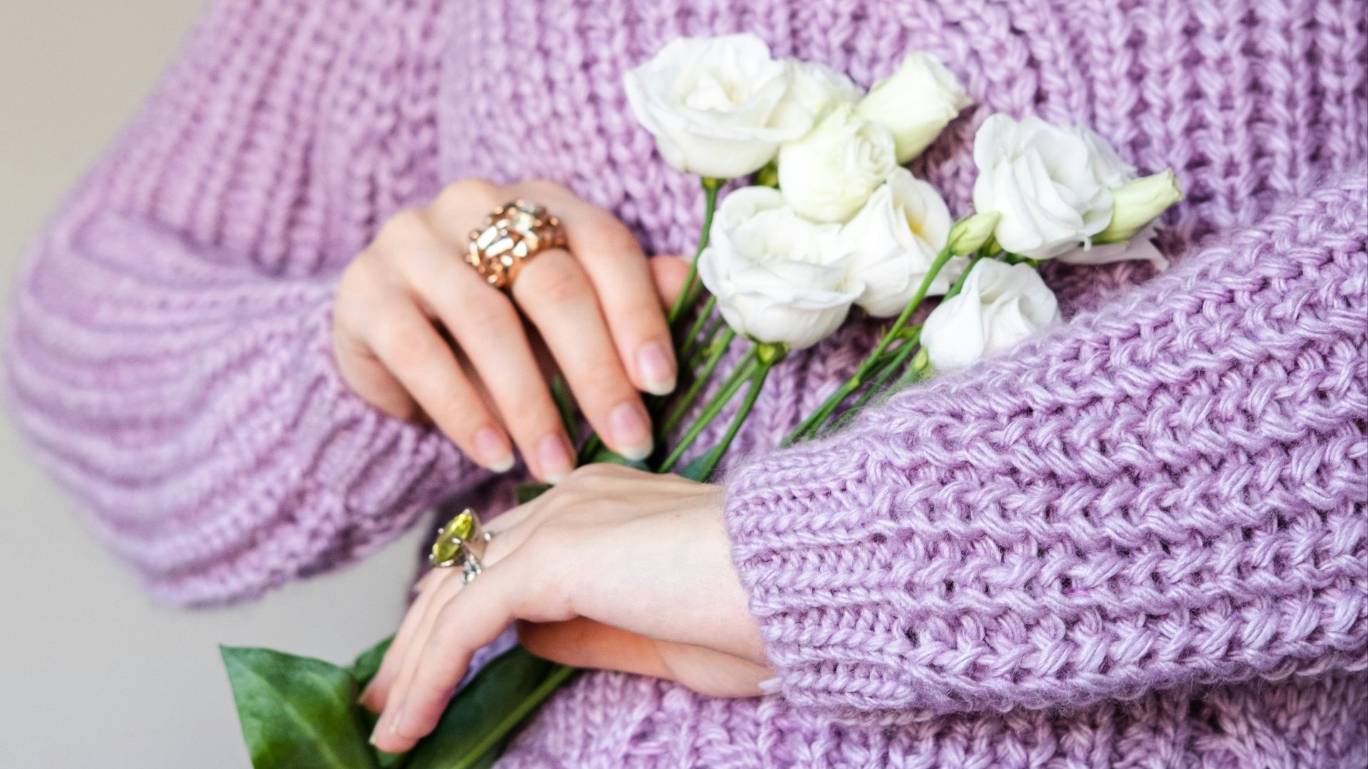 a woman in a purple sweater holding a bouquet of flowers