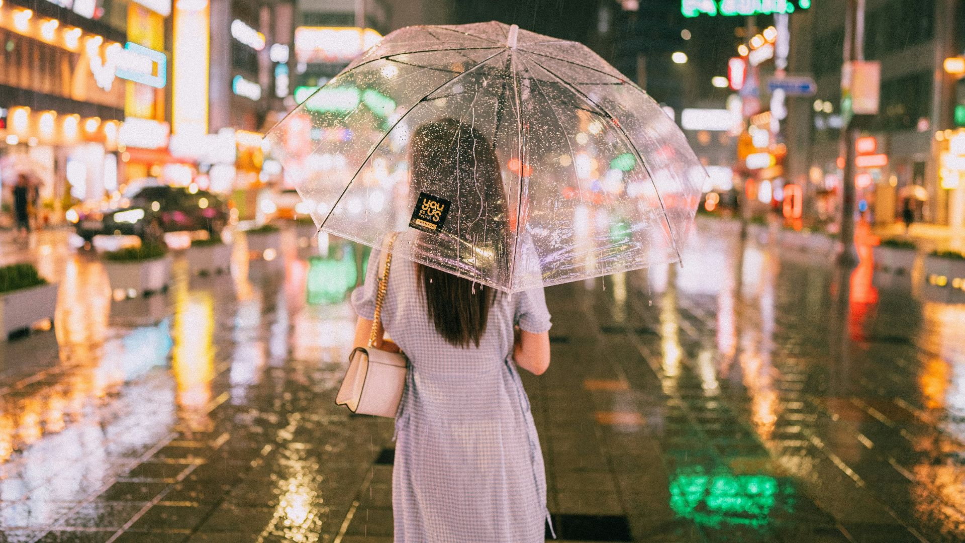 A woman walks in the rain with an umbrella.