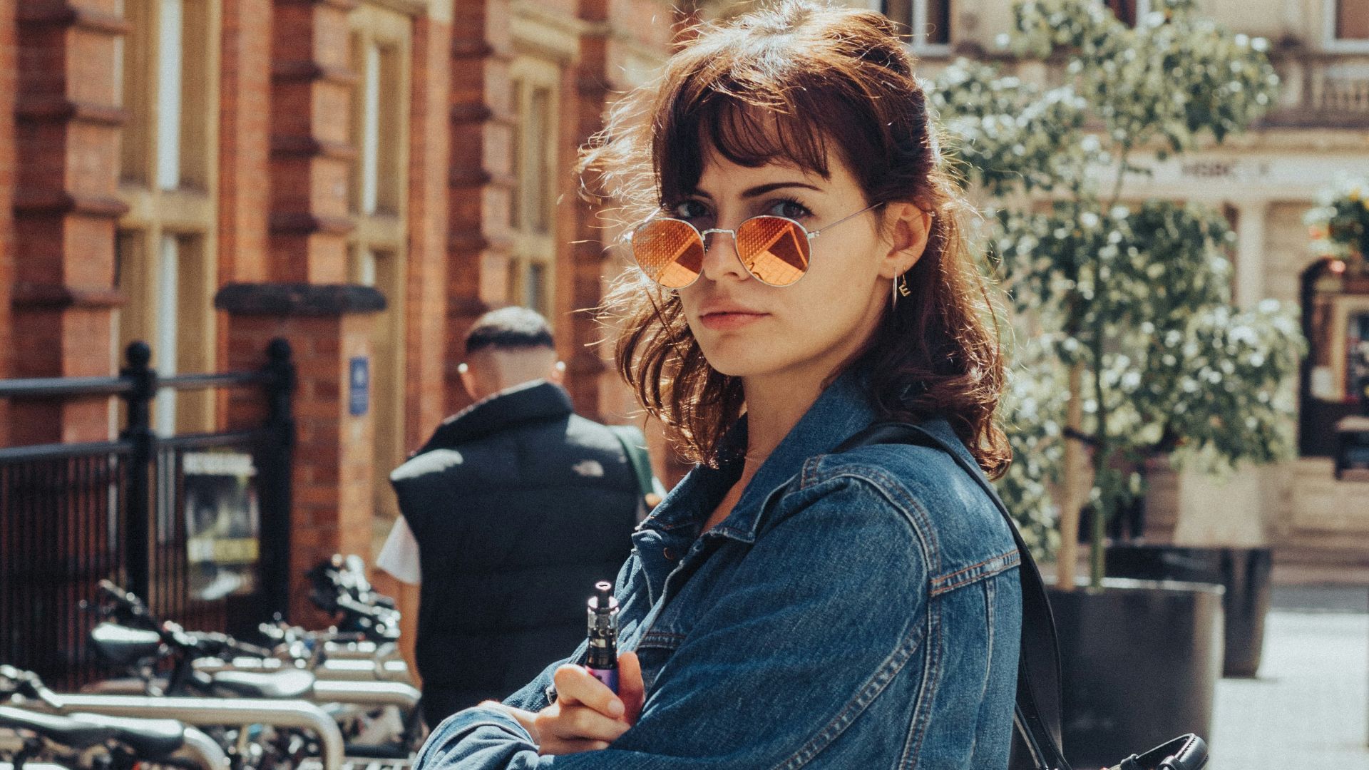 woman in blue denim jacket standing beside bicycle during daytime