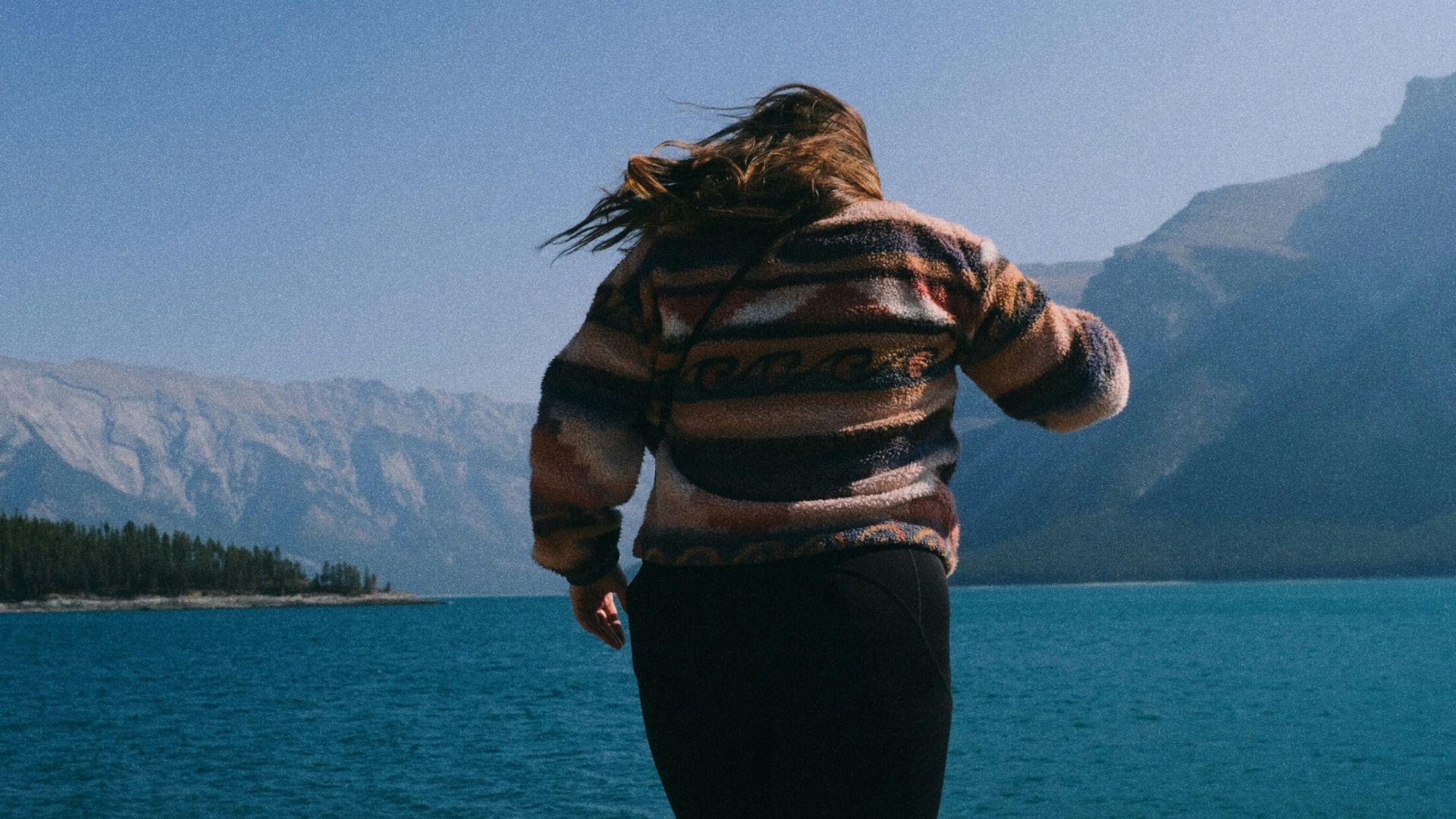 Woman standing on rocks overlooking a turquoise lake