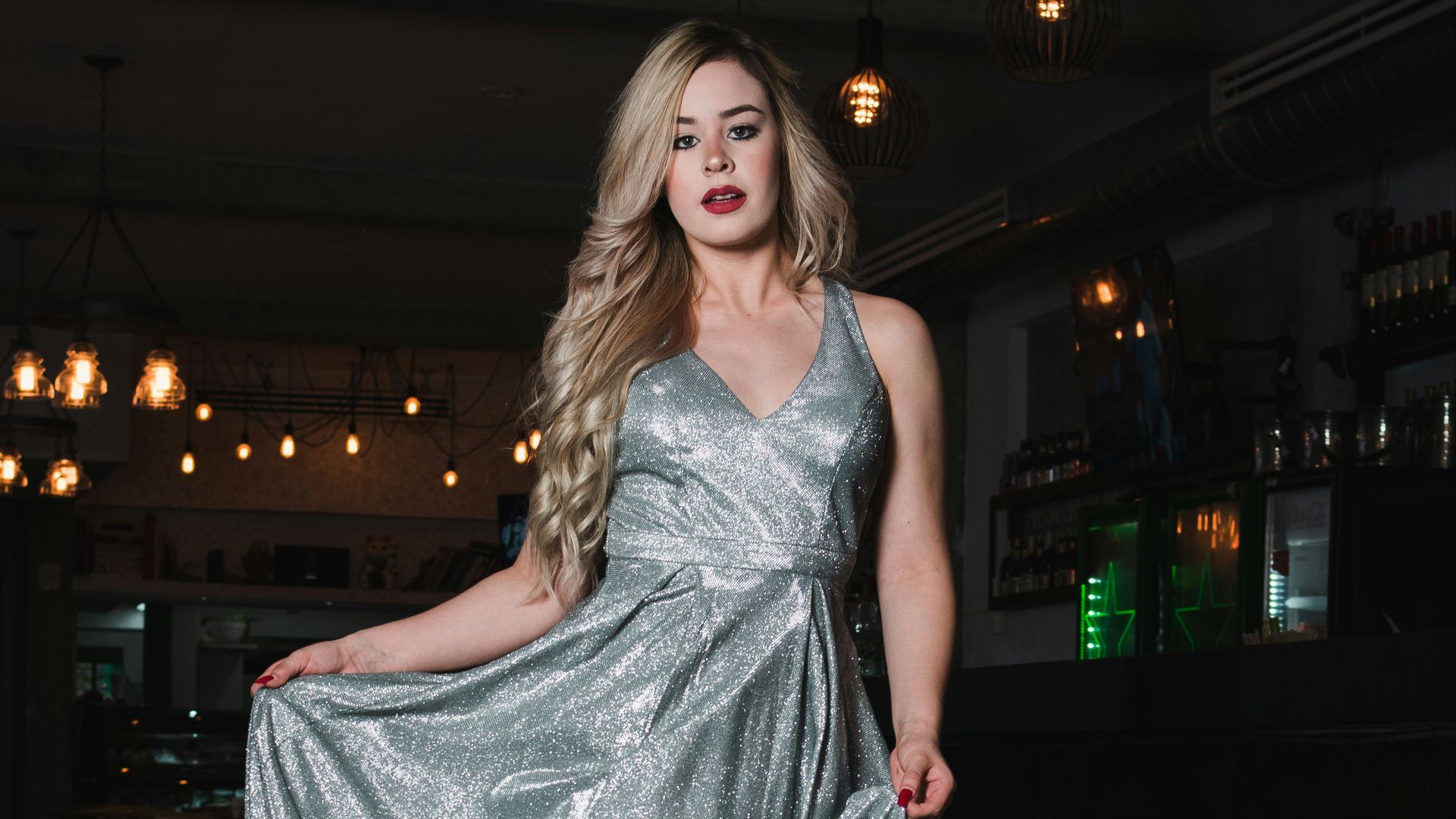 Woman in a shimmering silver dress walks indoors.