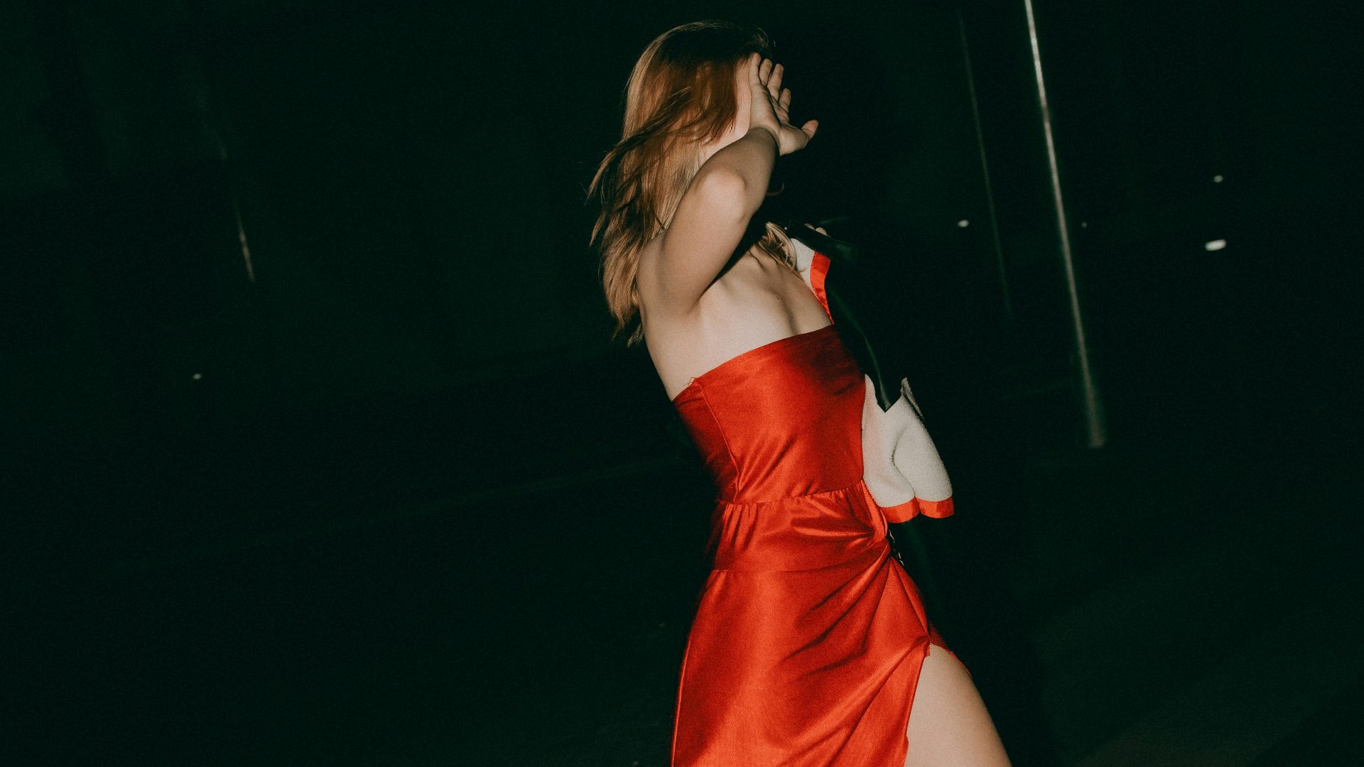 Woman in red dress walks at night.