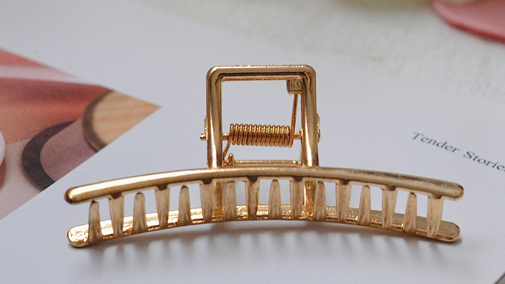 A gold hair claw is placed on a white surface.