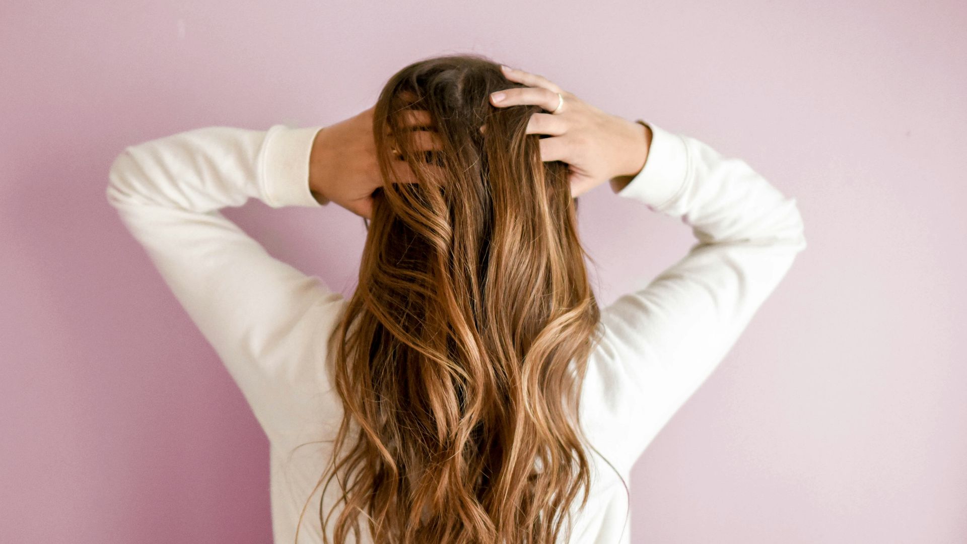 woman in white long-sleeved shirt standing in front of pink wall