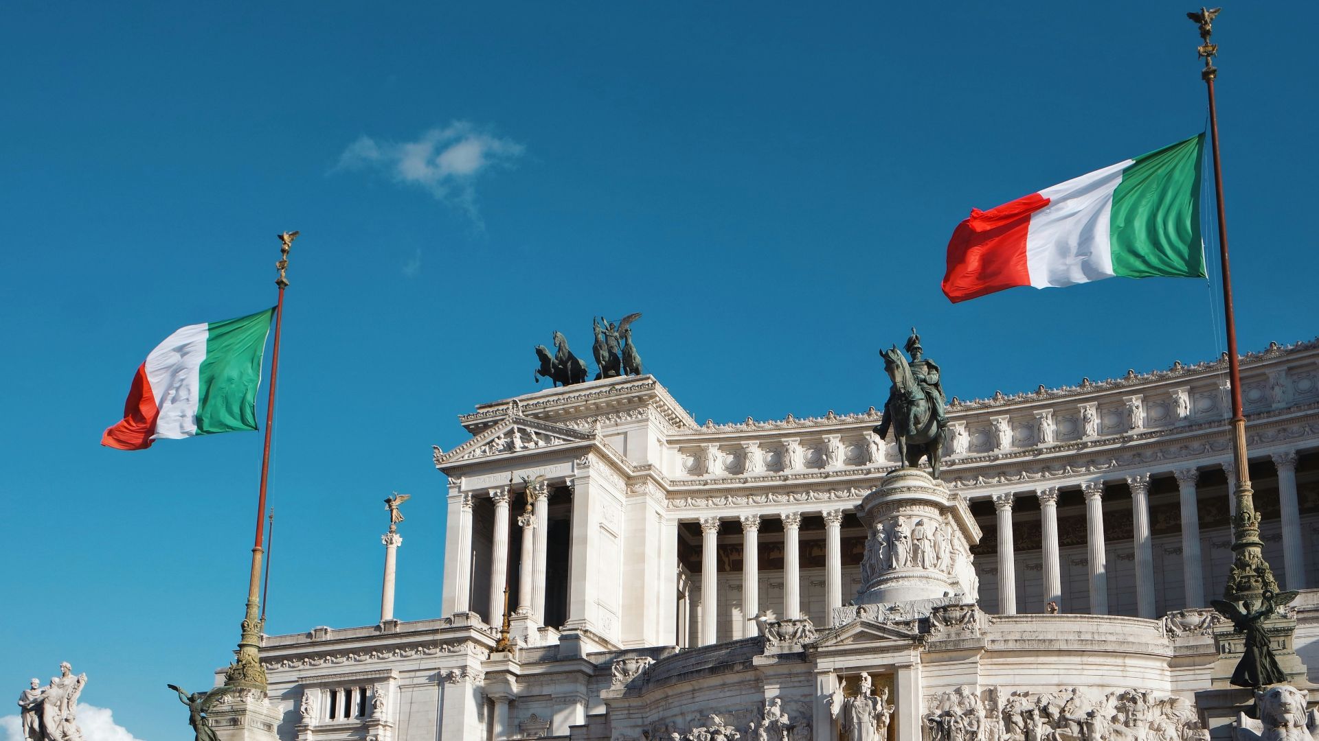white concrete building with red flag on top under blue sky during daytime
