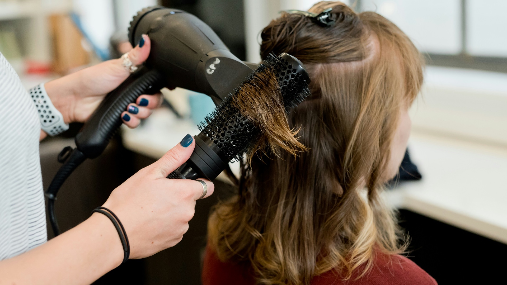 woman in red long sleeve shirt holding hair blower