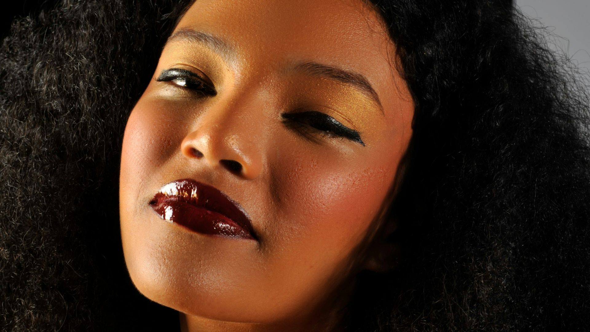 Woman with dark curly hair and glossy lips