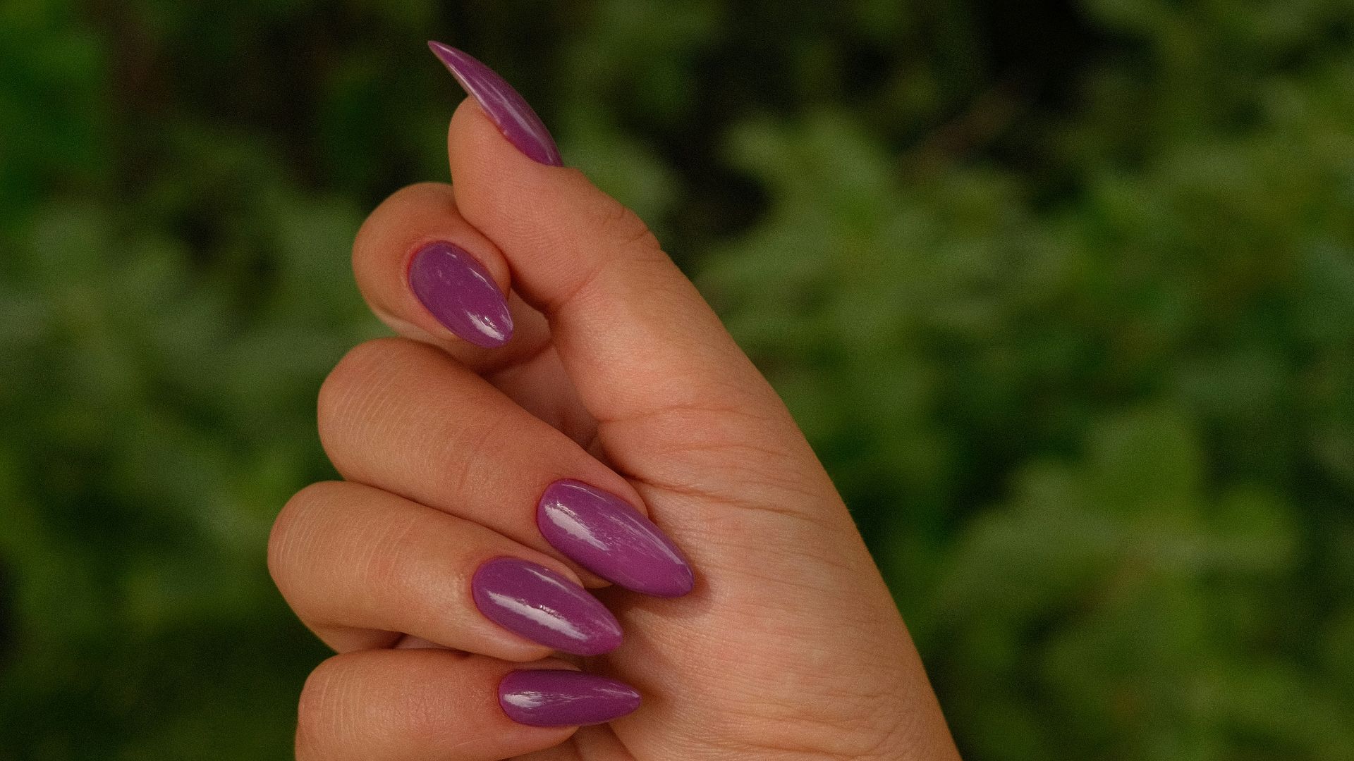 A hand displays painted purple nails.
