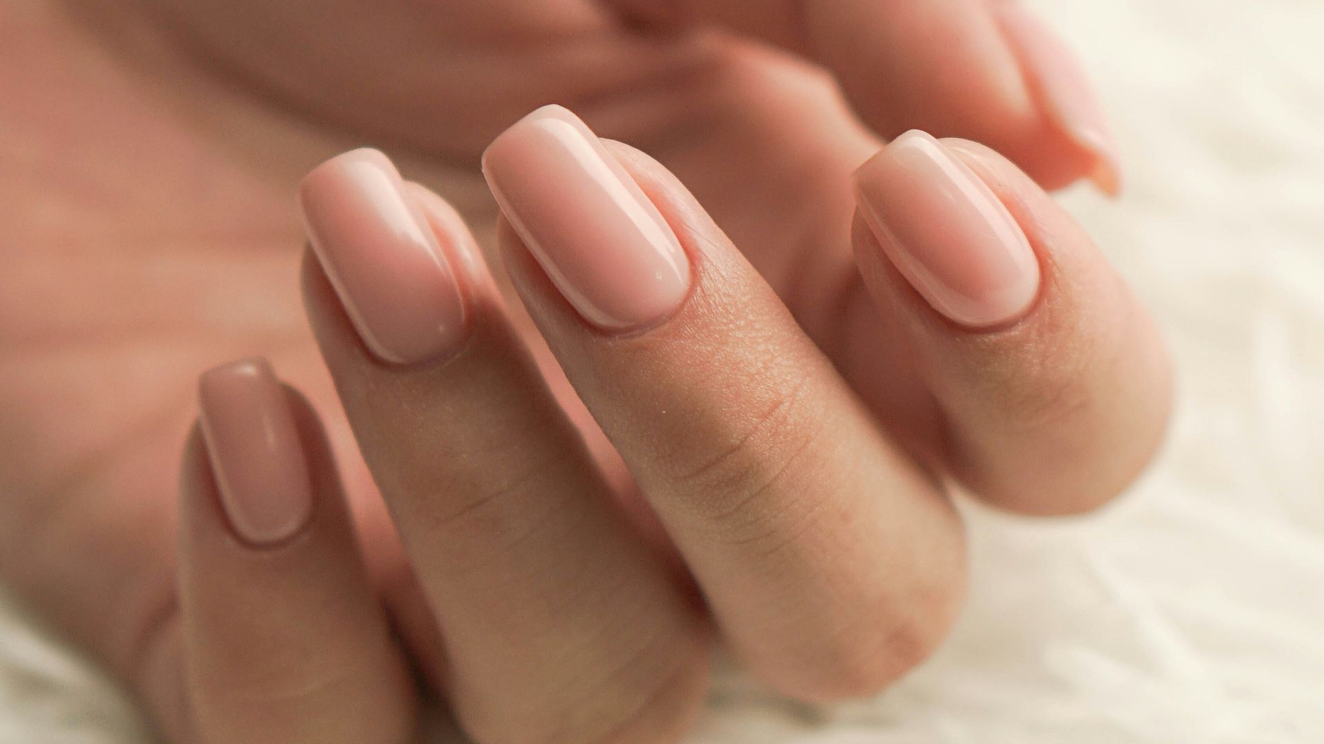 a woman's hand with a pink manicure on it
