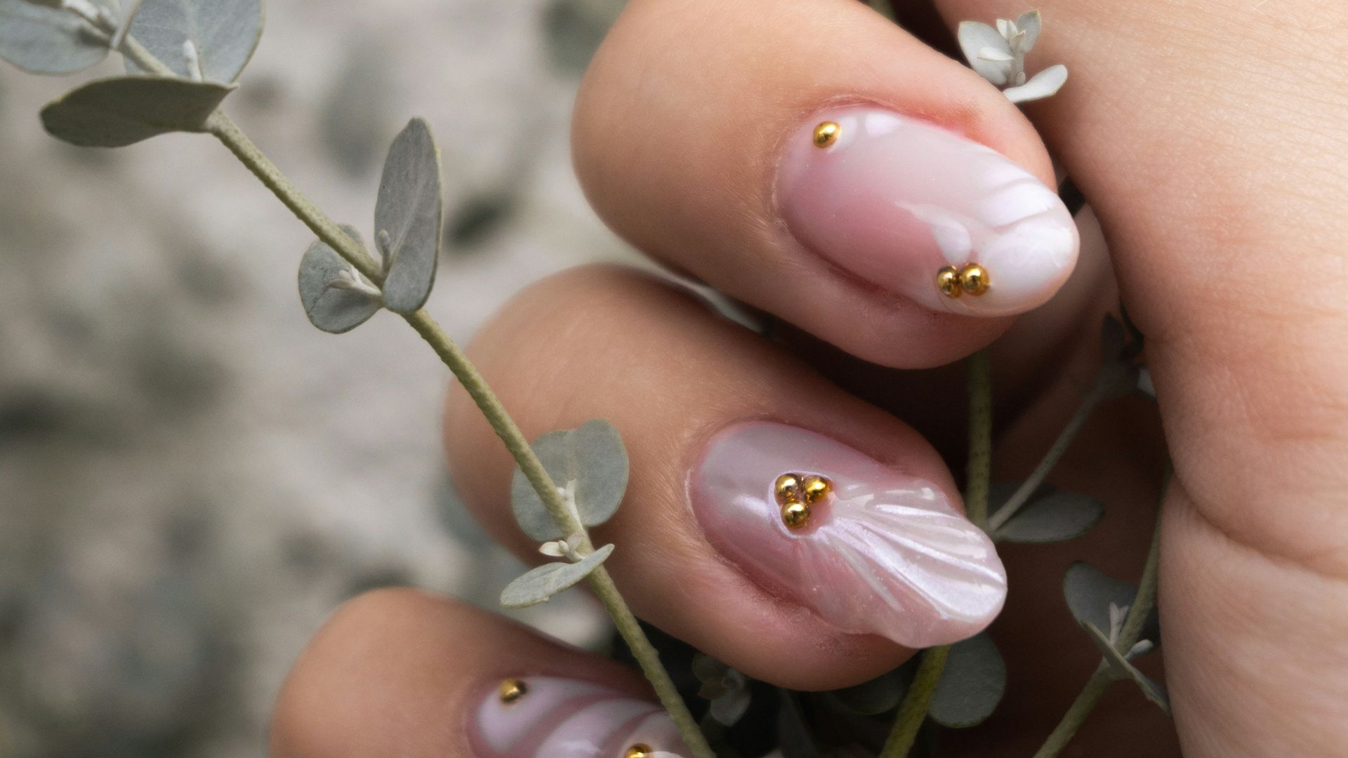Woman's hand with ornate nails holding a delicate plant