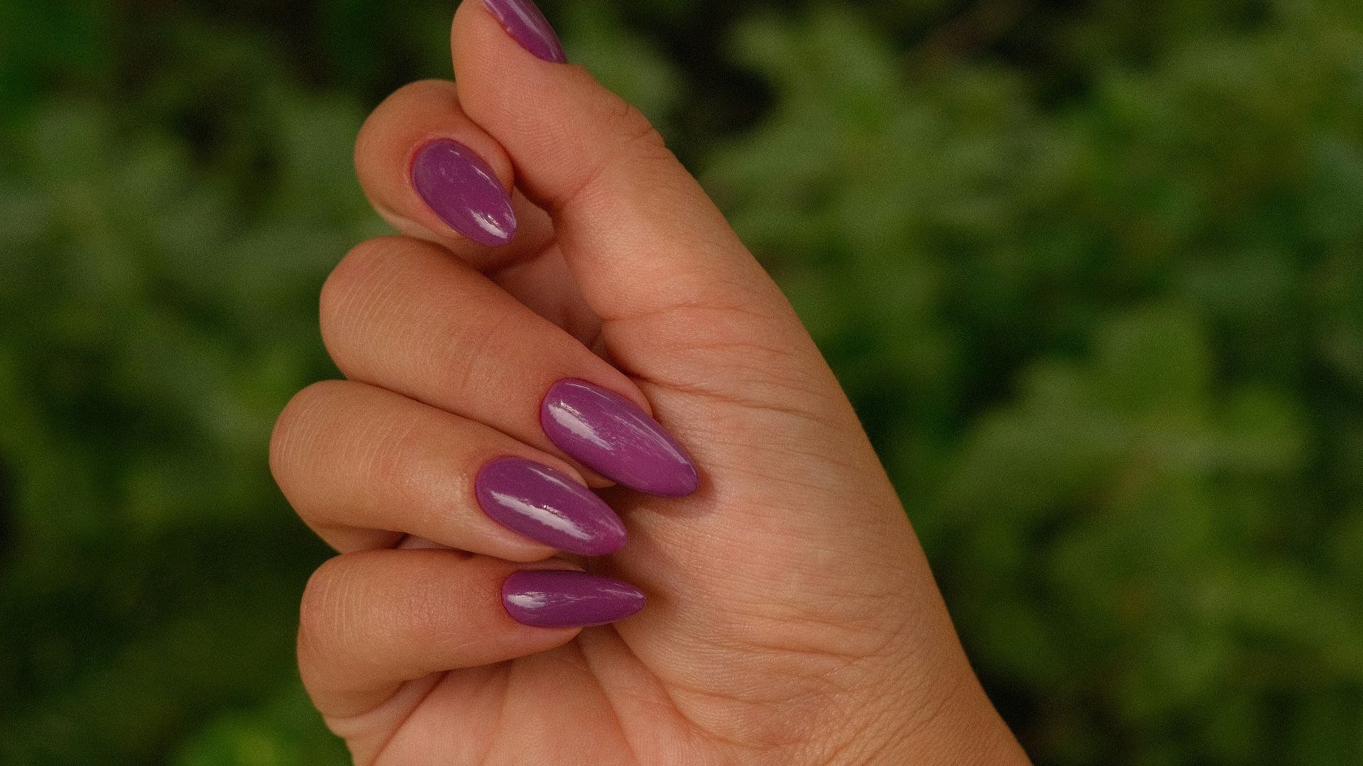 A hand displays painted purple nails.