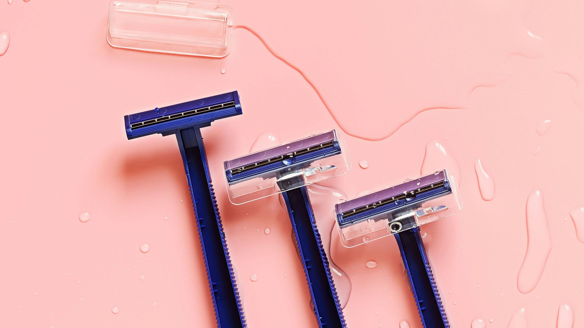 Three blue toothbrushes sitting on top of a pink surface