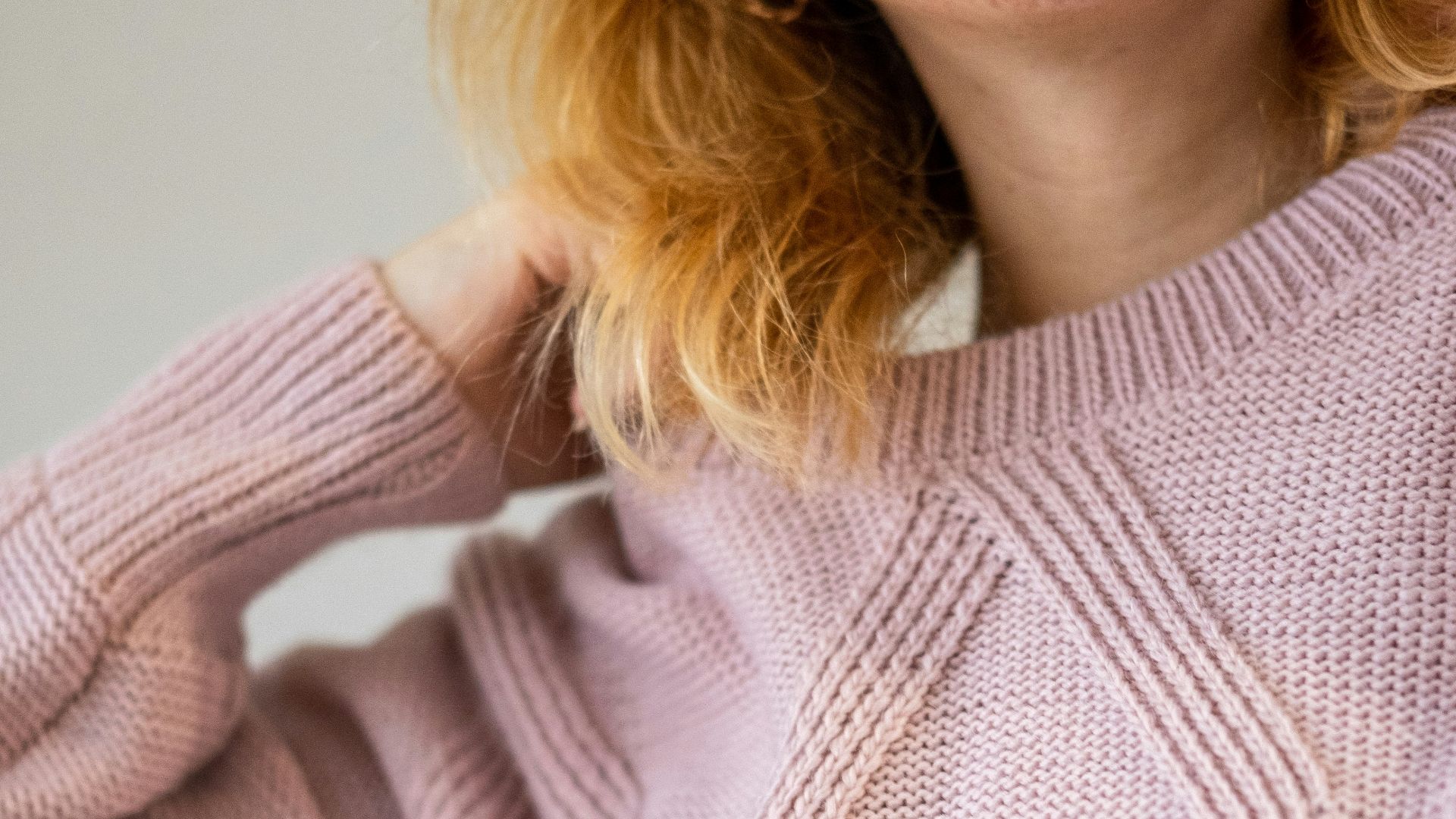 a woman with red hair wearing a pink sweater