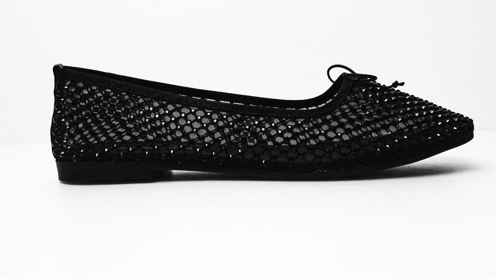 A black woven flat shoe with a bow