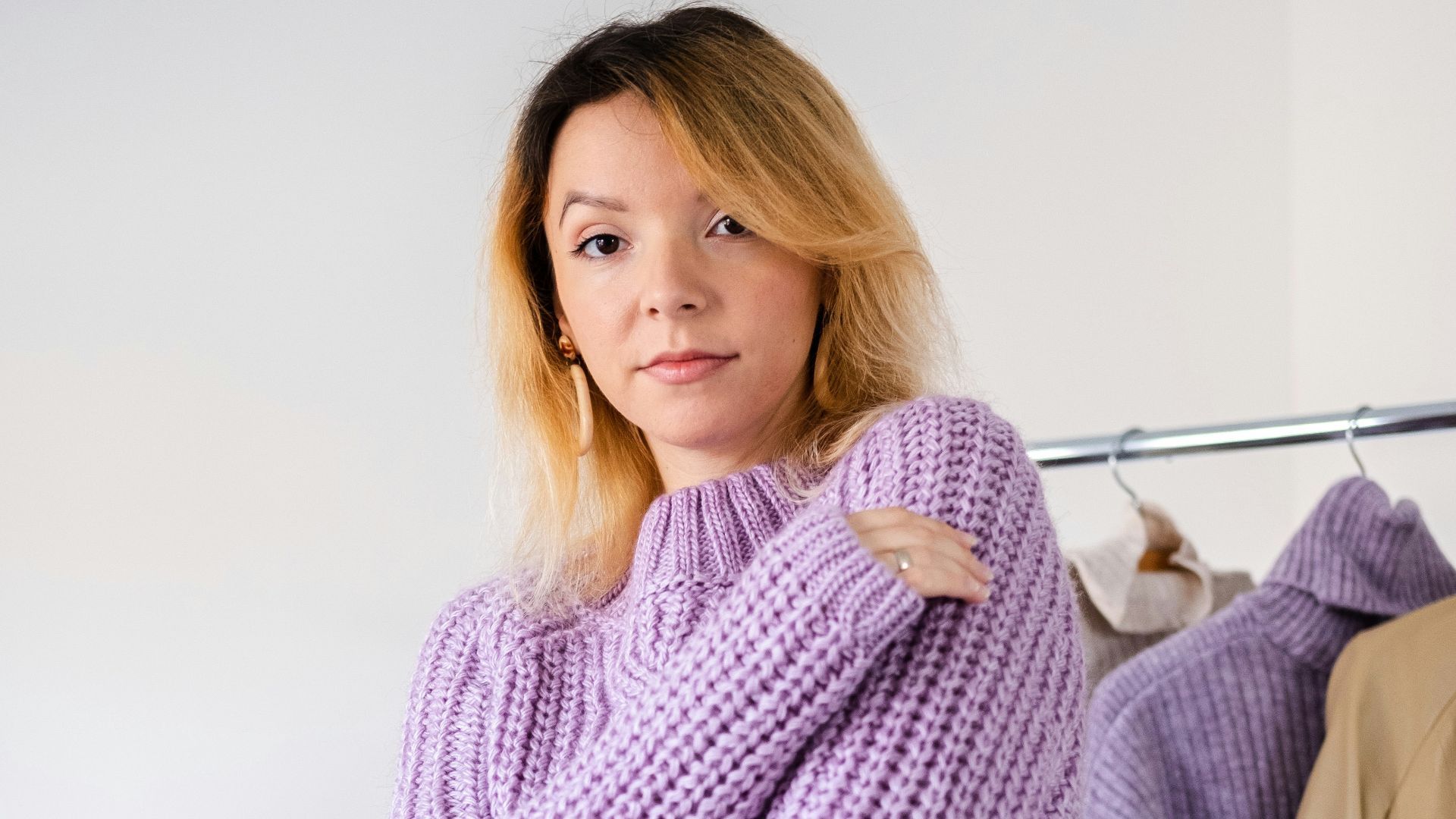 a woman standing in front of a rack of clothes