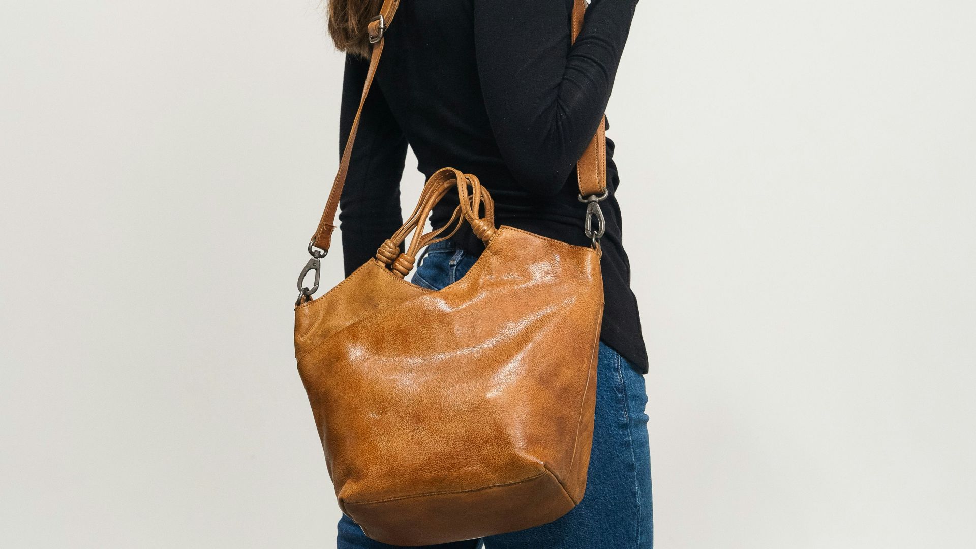 Woman in black shirt carrying a brown leather handbag
