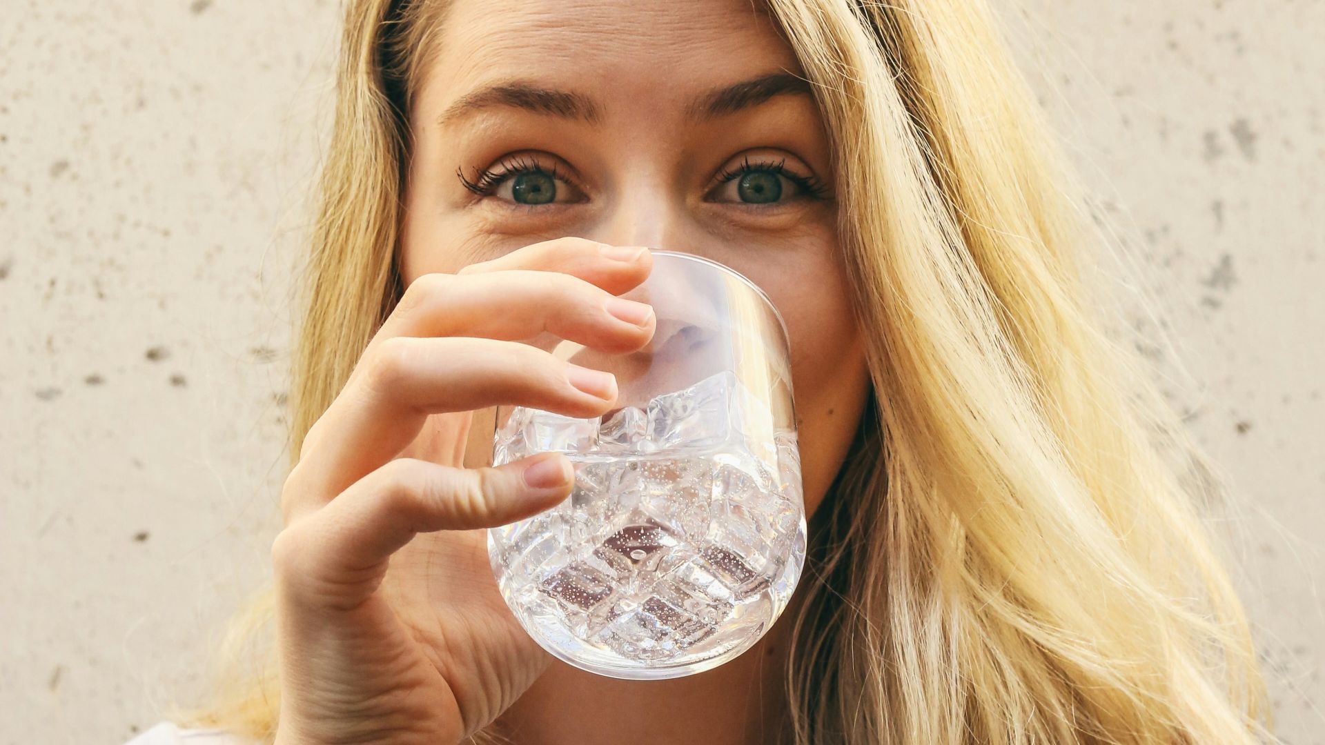 woman in white crew neck shirt drinking water