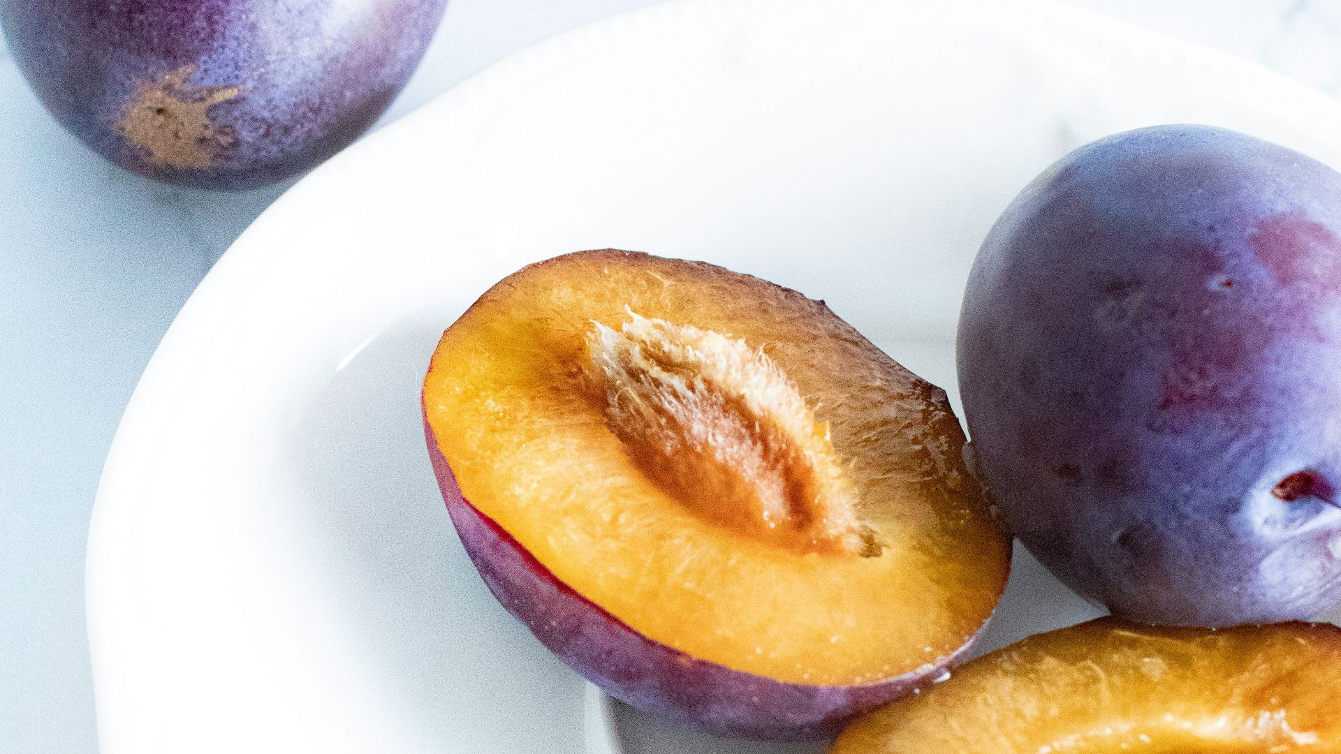 purple and yellow round fruits on white ceramic plate