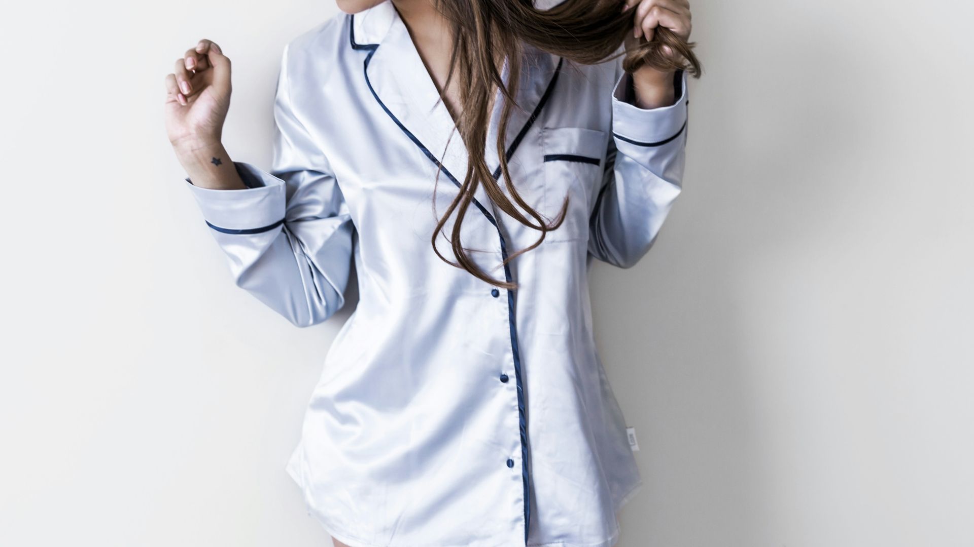 woman in white and black button-up coat leaning on wall