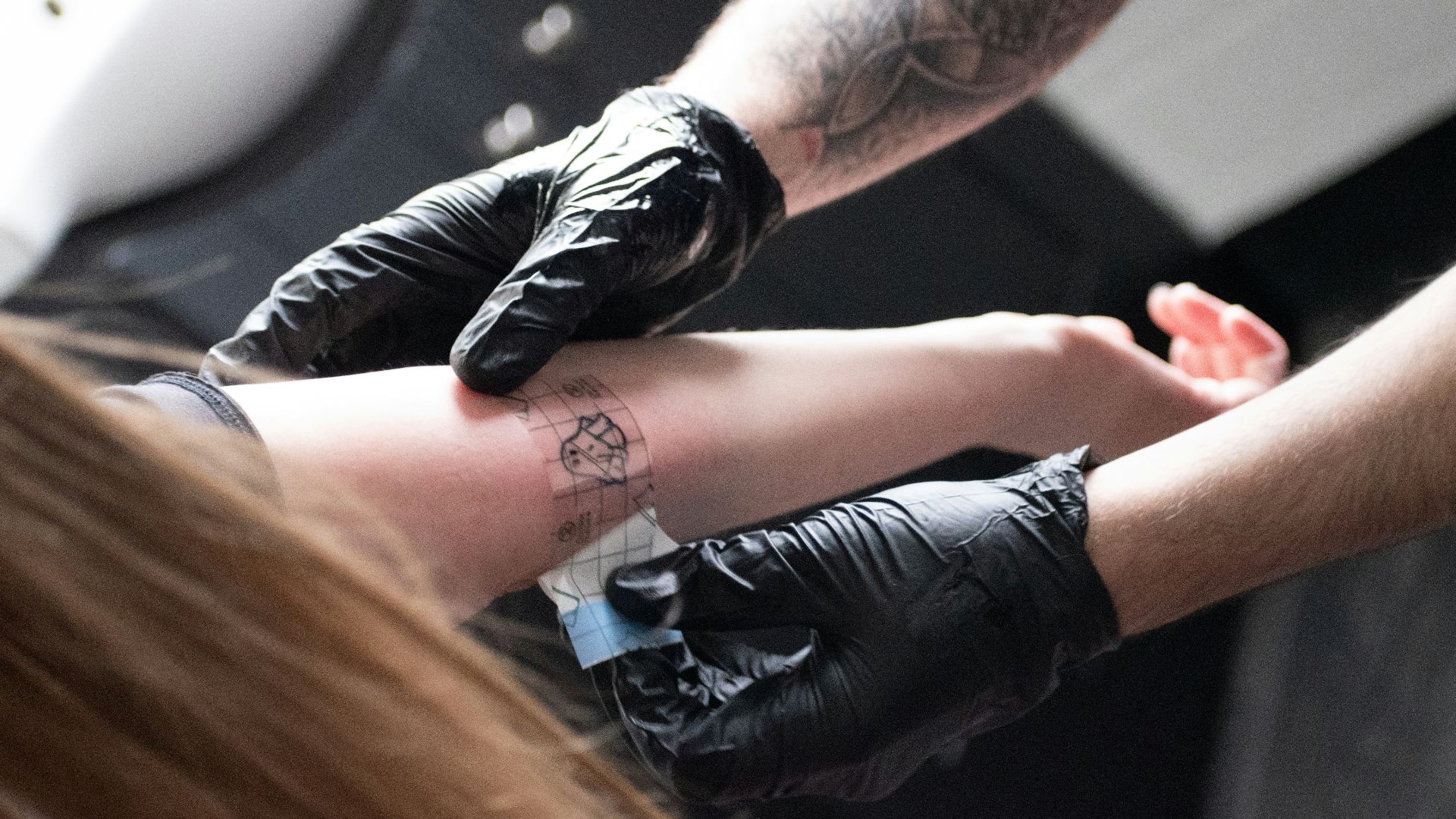 A tattoo artist is giving a tattoo.