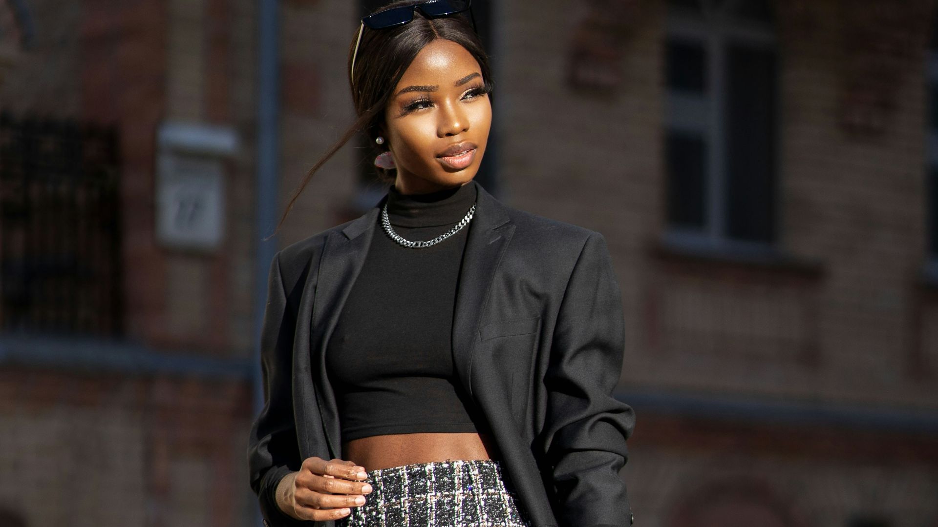 woman in black blazer and black and white skirt standing beside black metal stand