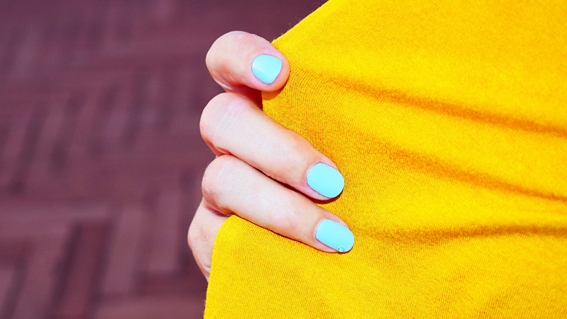 person with blue manicure holding orange textile