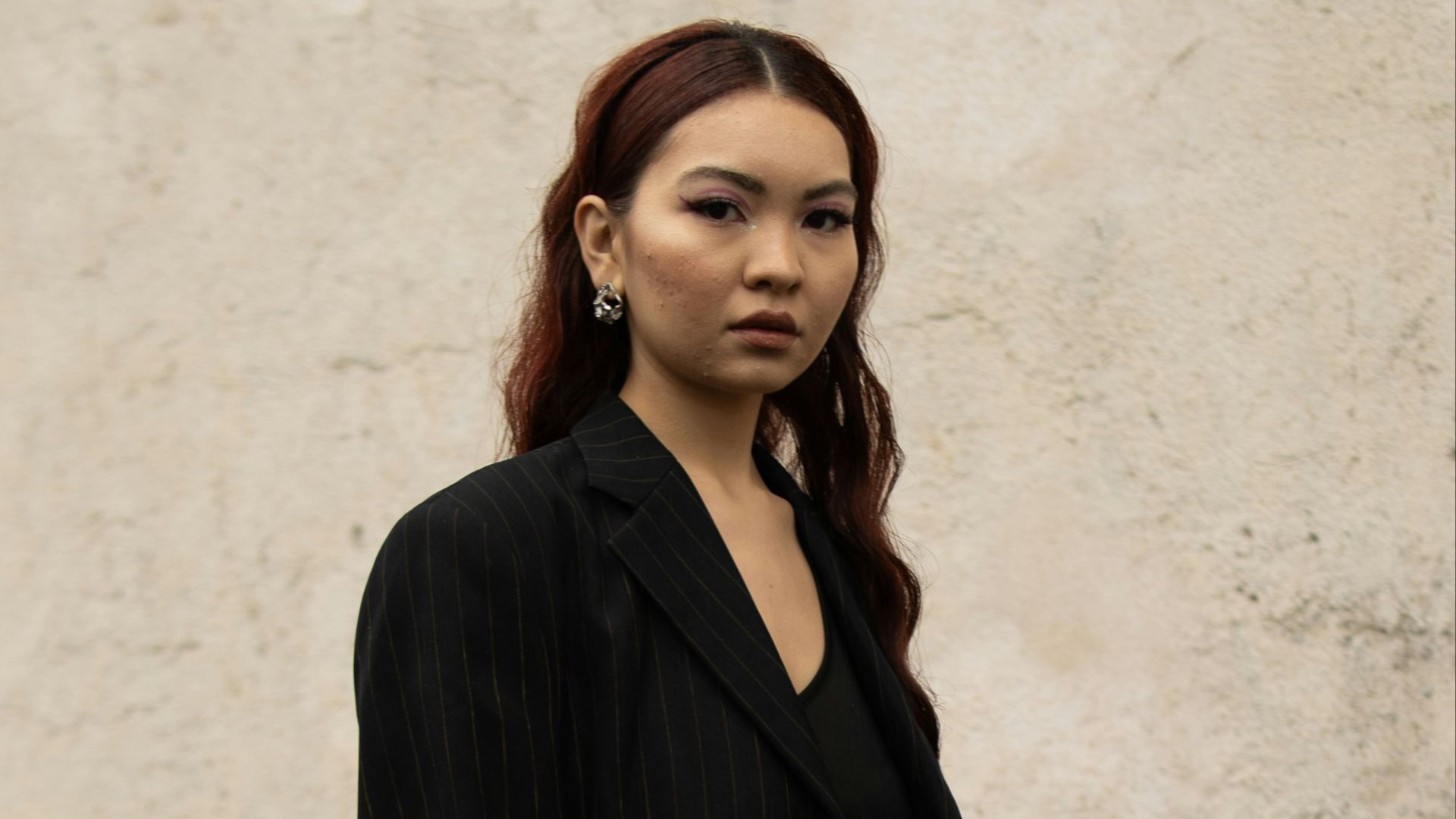 A woman standing in front of a white wall