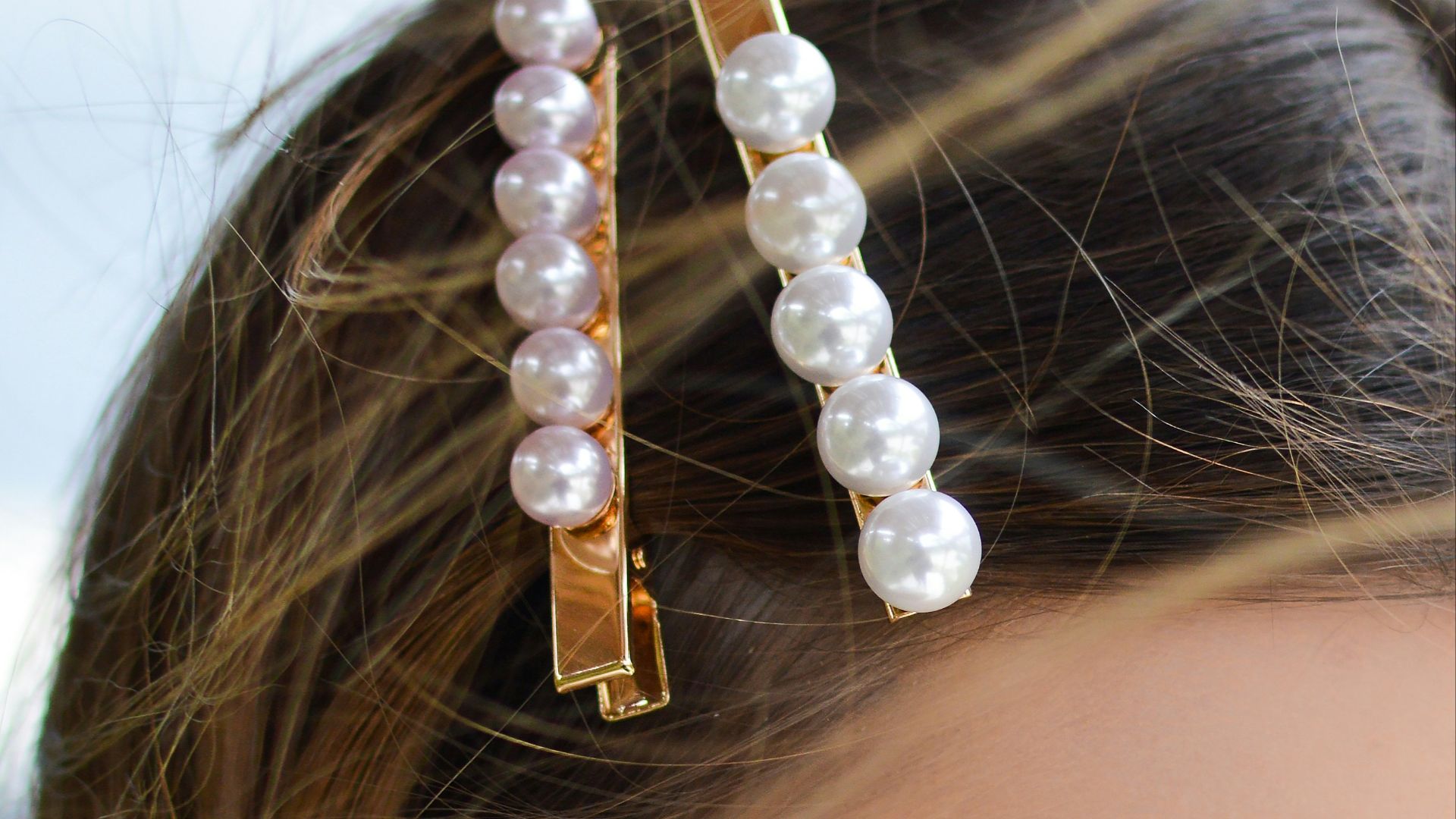 woman with two beaded clips clipped on her hair looking downwards