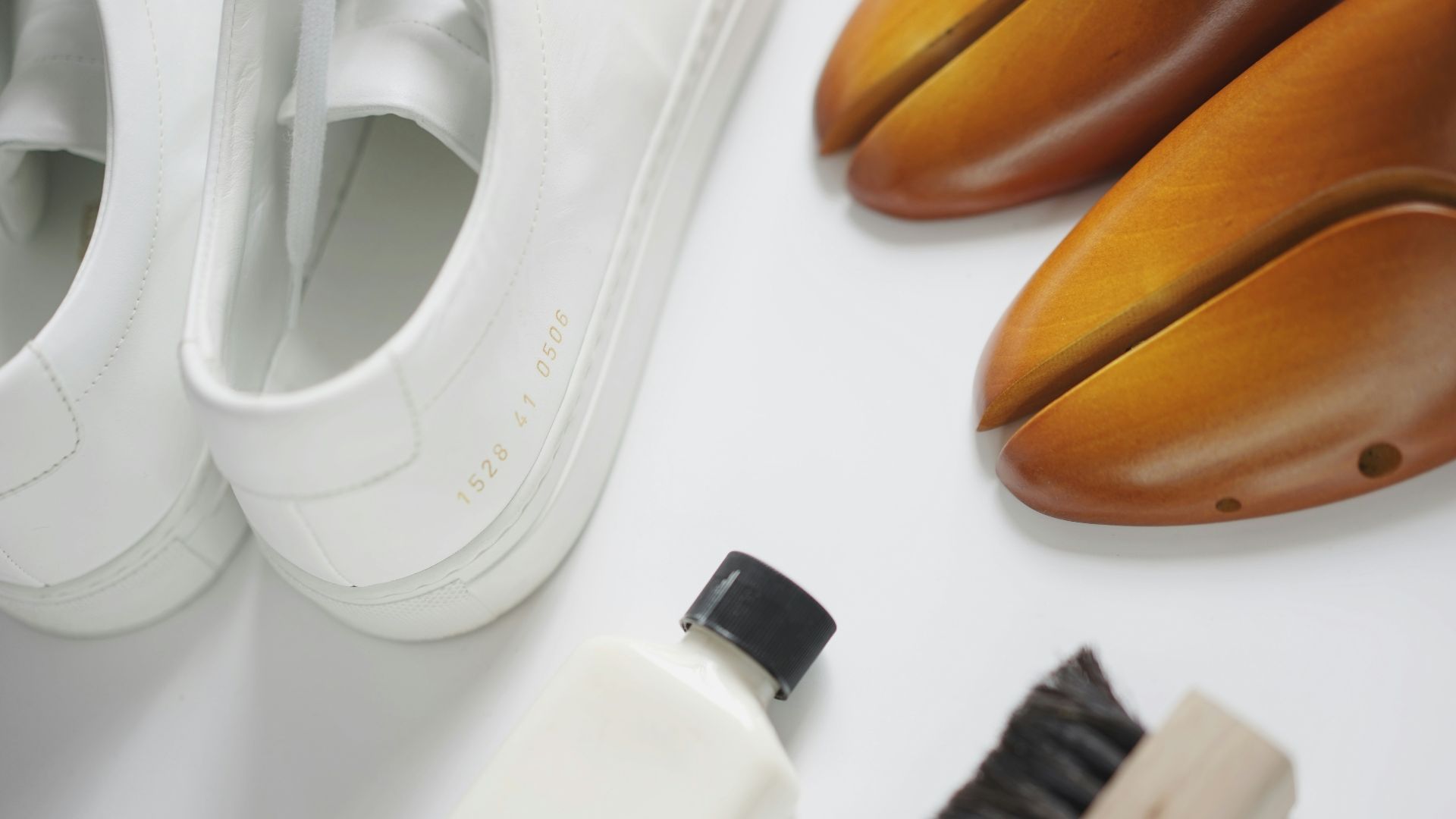 a pair of white shoes next to a white shoe brush