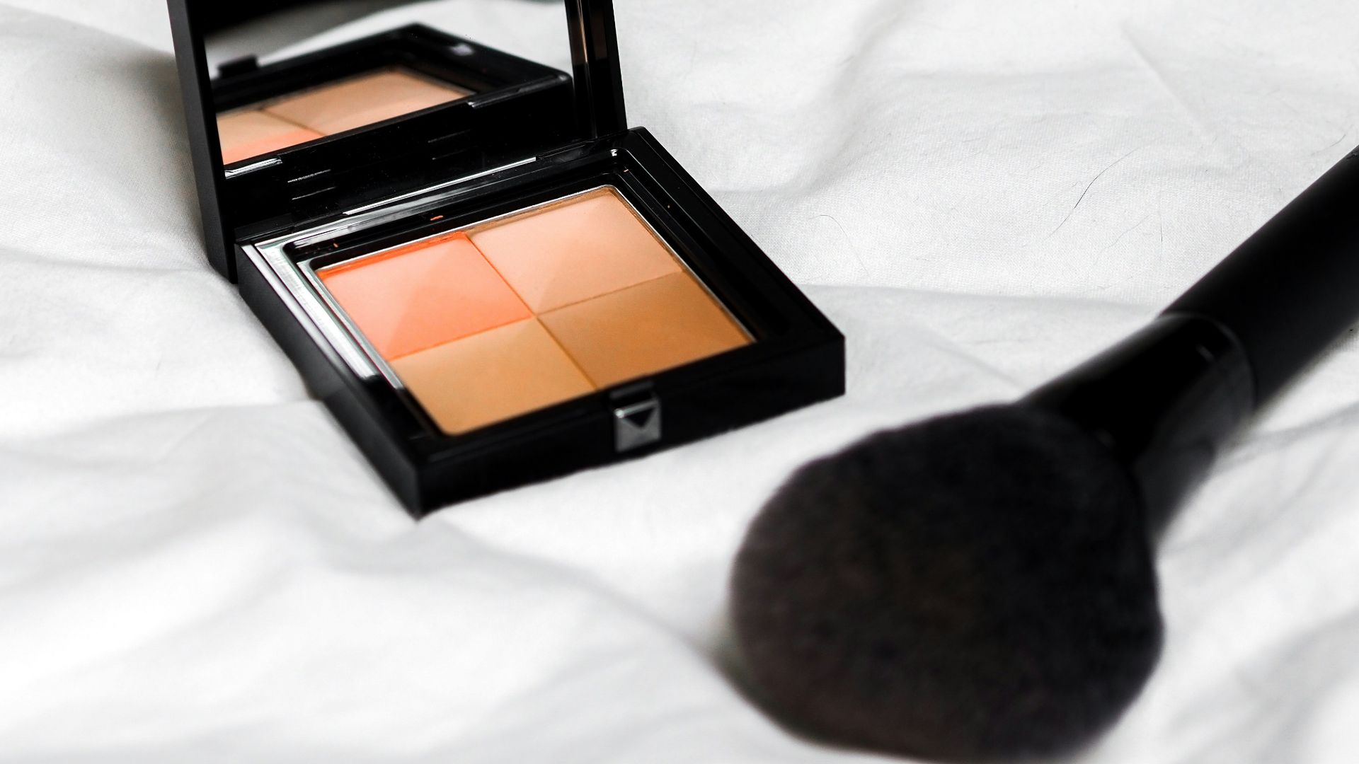 black and brown makeup palette on white textile