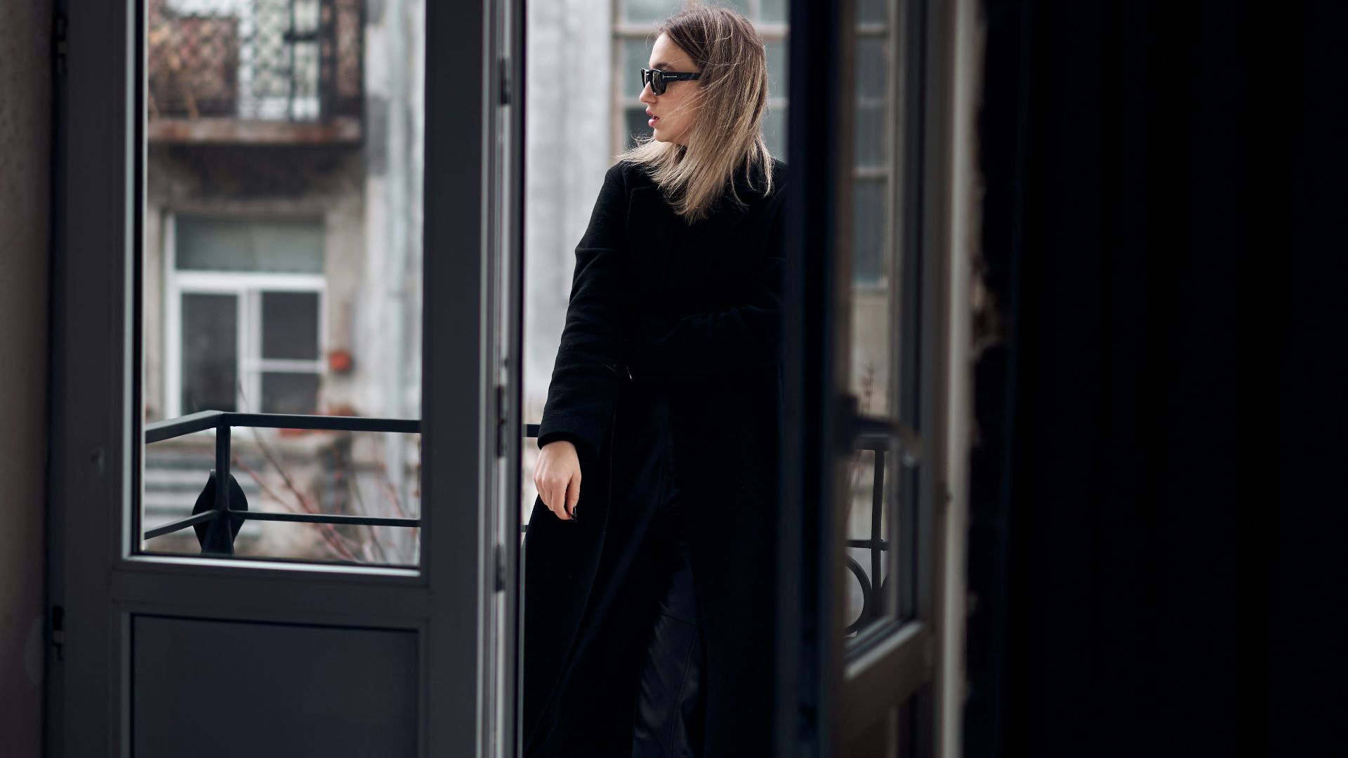woman in black coat standing in front of glass window