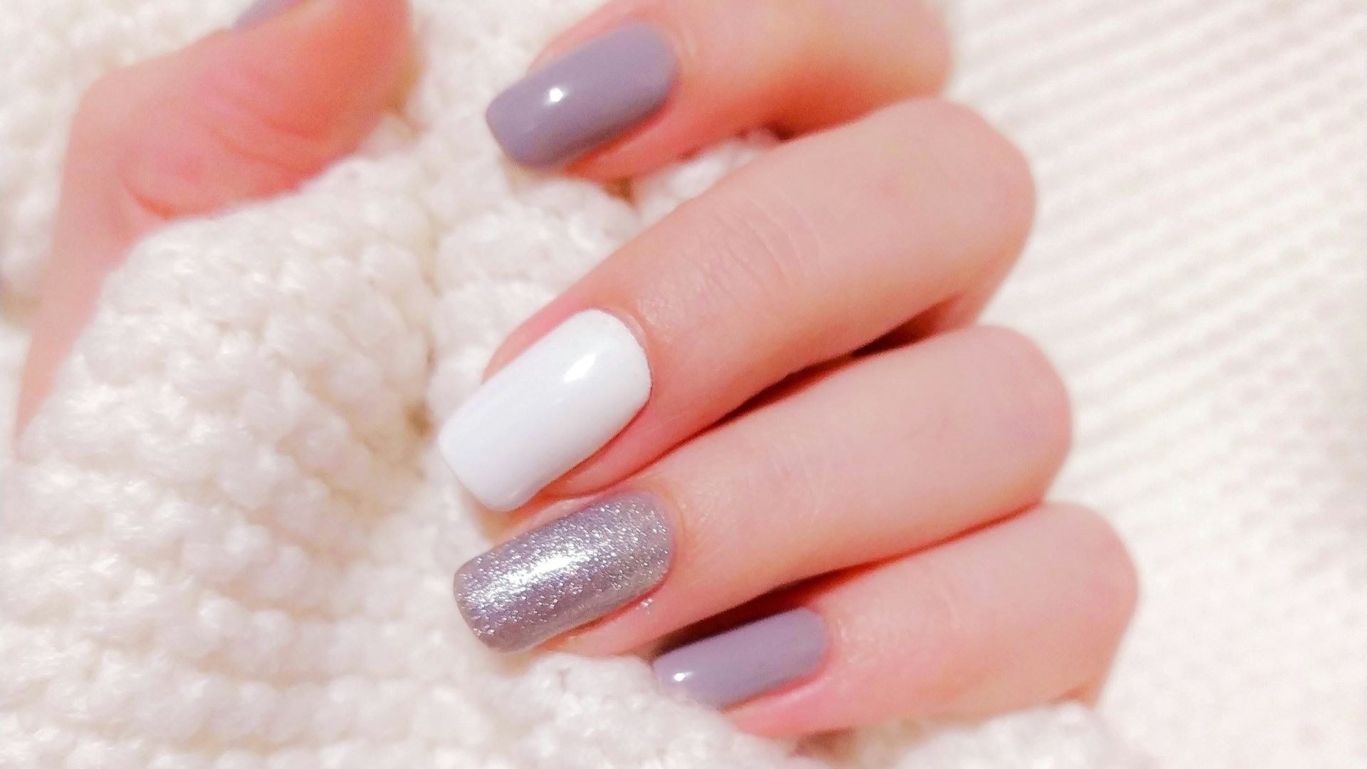 person with pink manicure on white textile