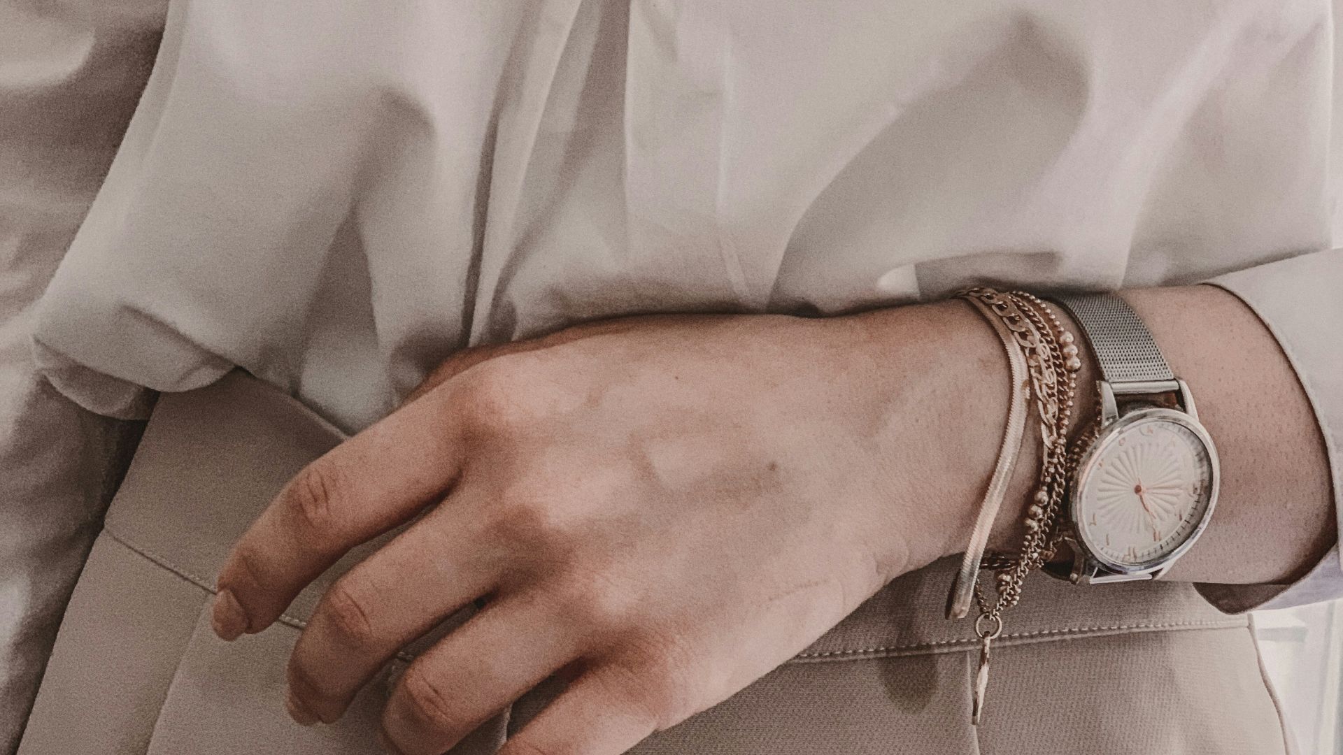 person in white dress shirt wearing silver link bracelet round analog watch
