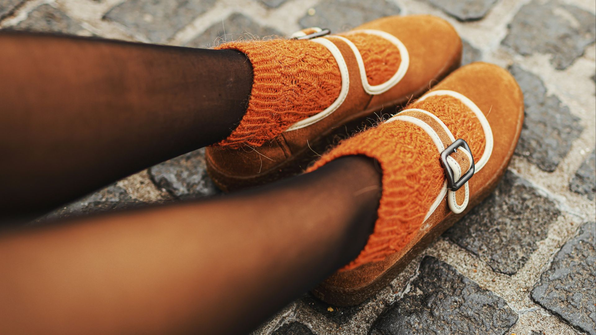 Brown monk strap shoes with orange socks.