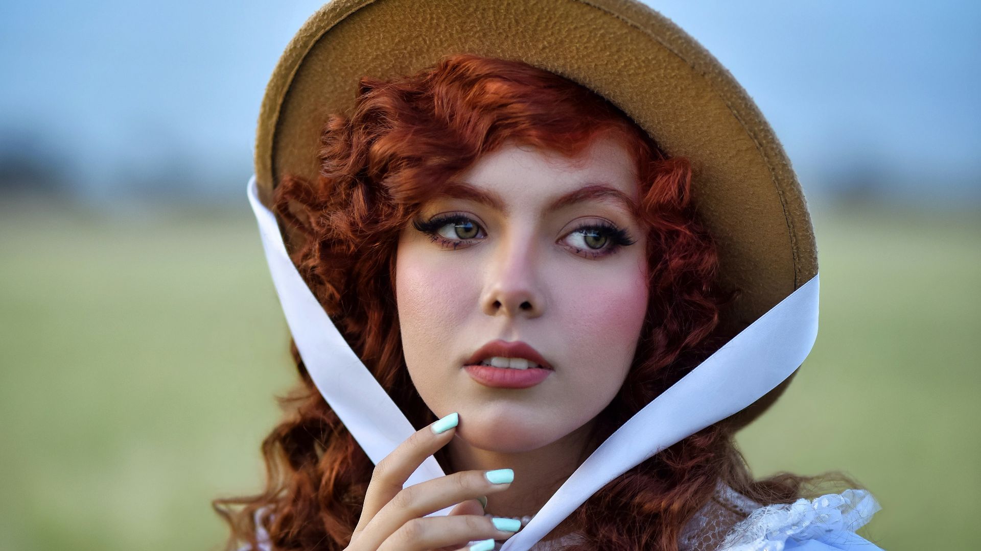 A woman with red hair wears a vintage hat.