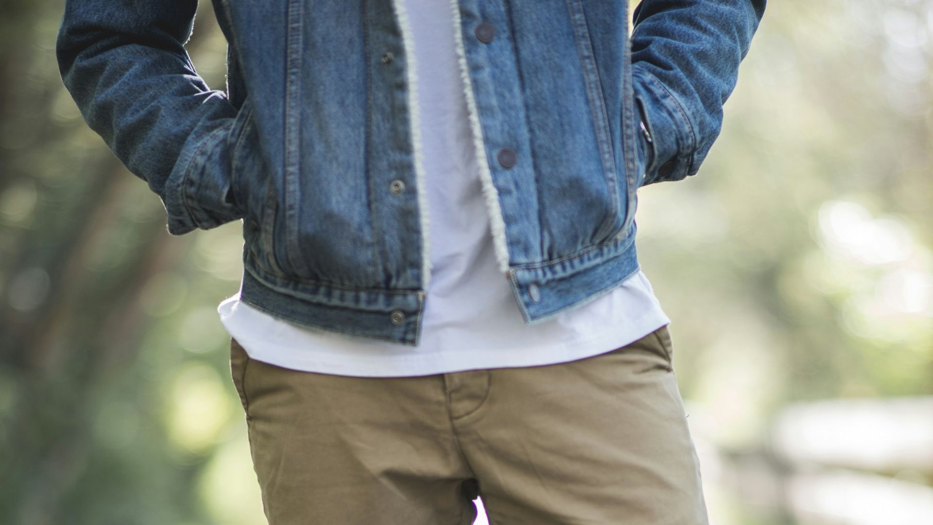 man wearing brown fitted jeans and sneakers standing on road at daytime