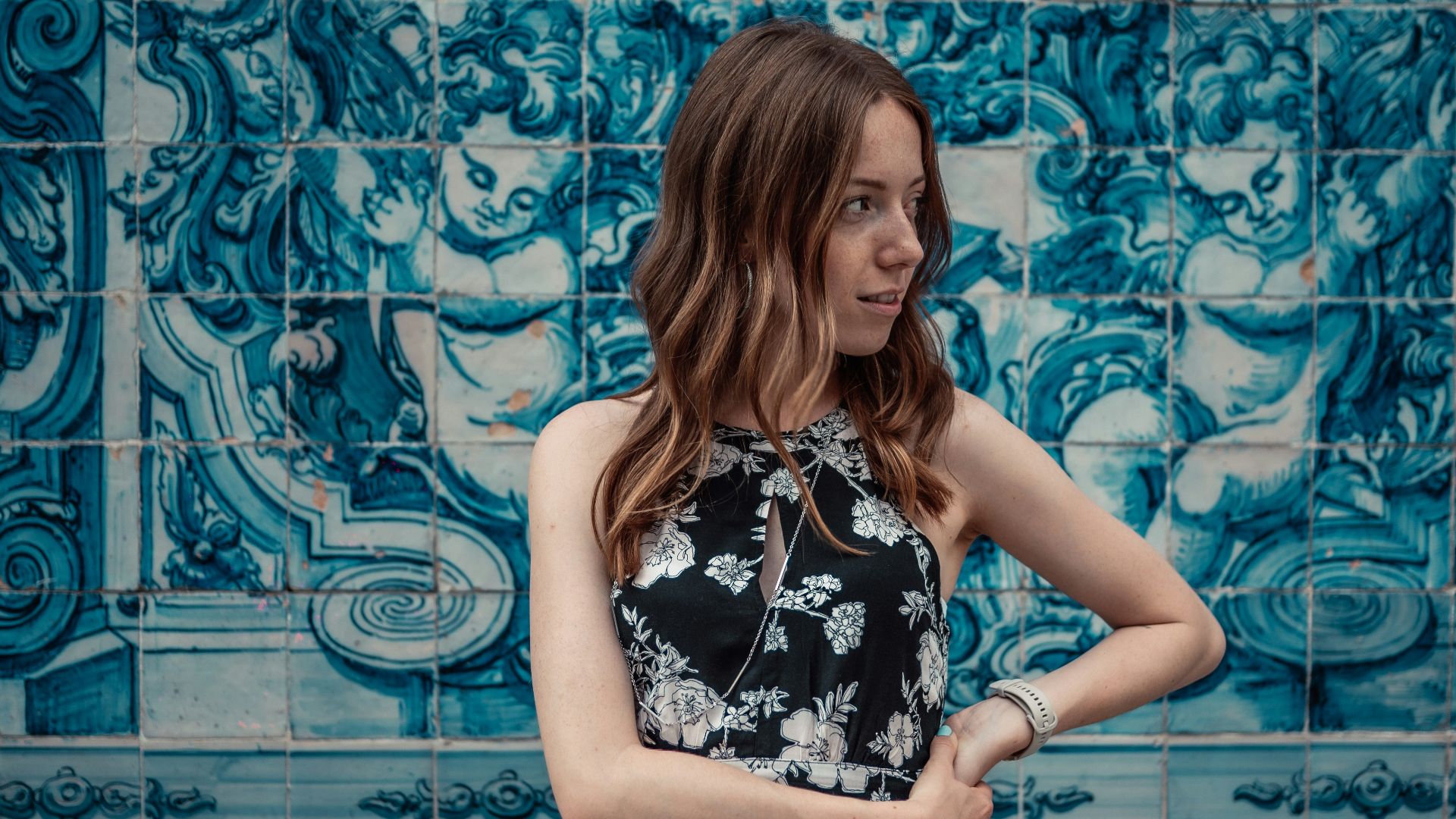 a woman standing in front of a blue tile wall