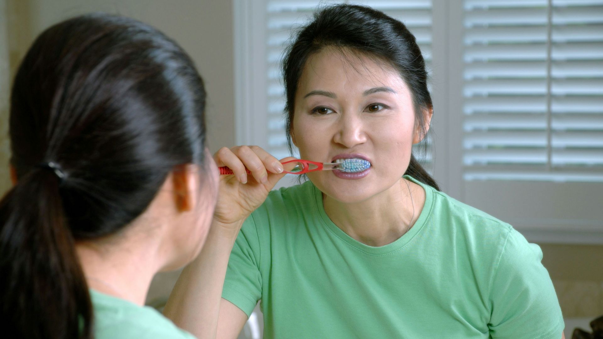 woman in green crew neck shirt holding red lollipop