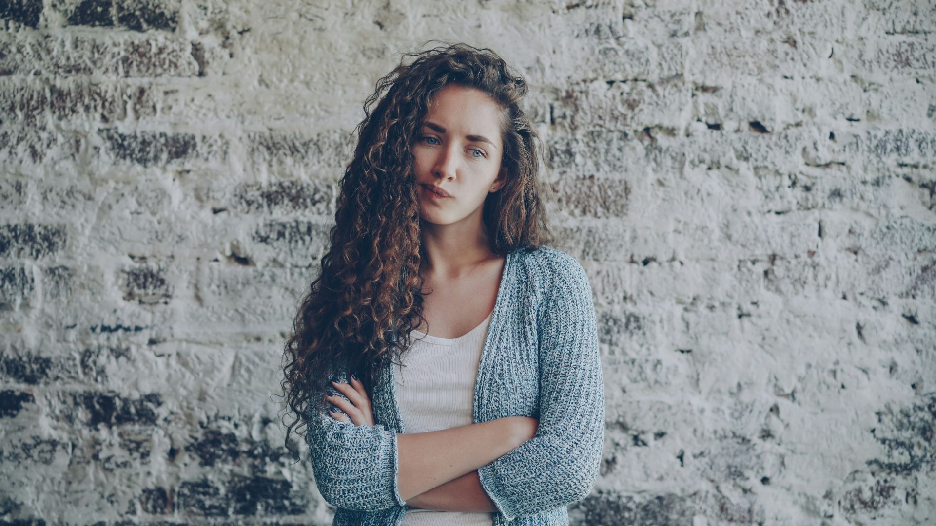 Young woman with curly hair crosses arms