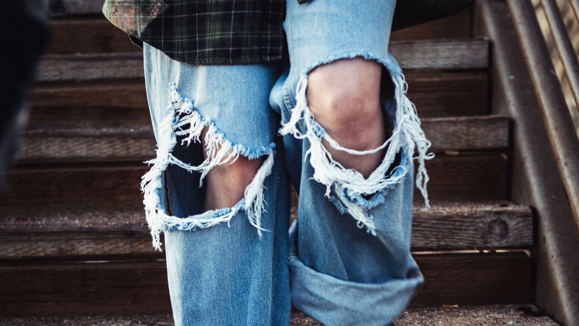 a person's legs in jeans and a blue shirt on a wooden staircase